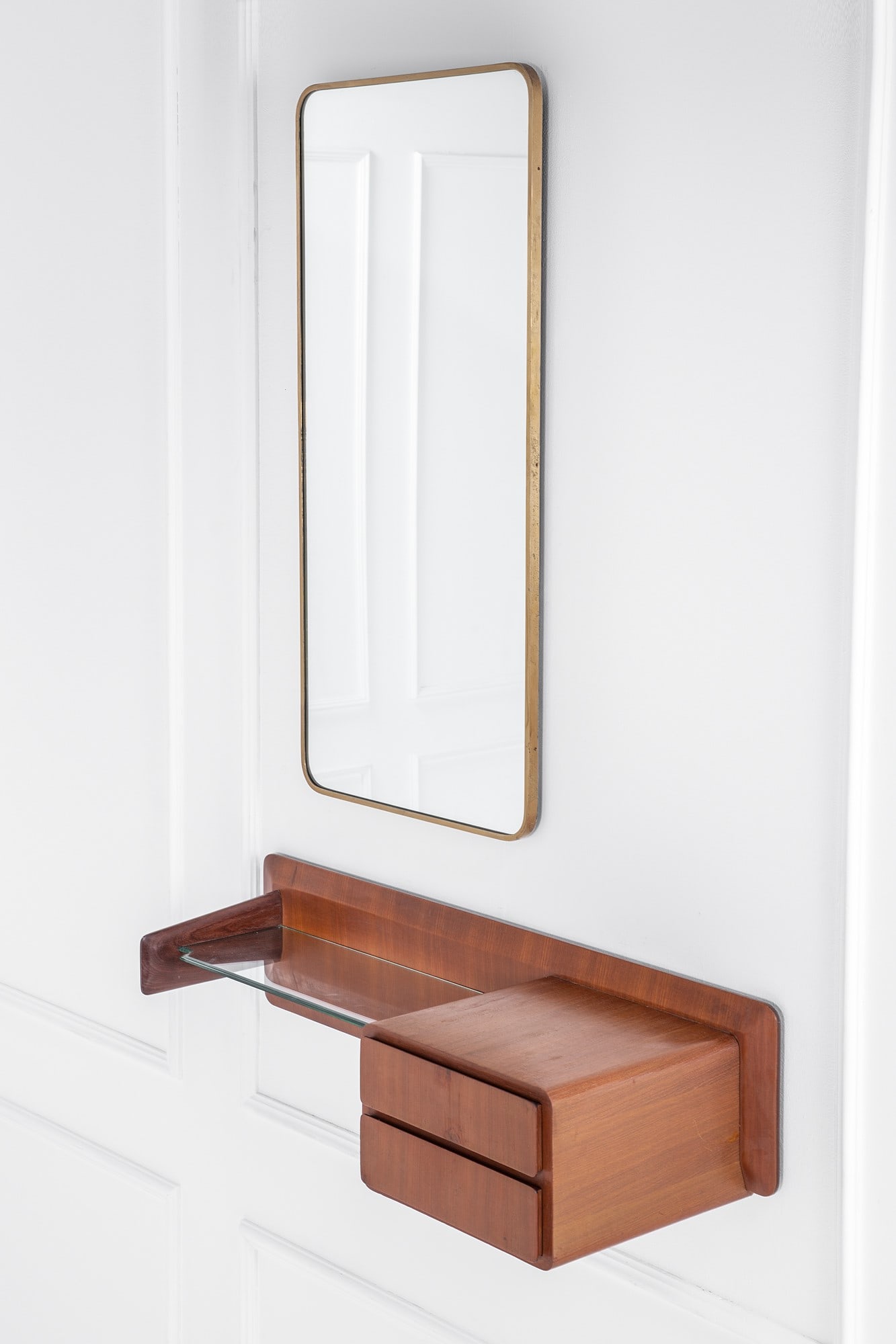 Console pensile con specchiera: Console pensile con specchiera Legno sagomato impiallacciato, cristallo molato, ottone, vetro specchiato. 1950 ca. Console cm 26x120x42, specchiera cm 118x57x4
