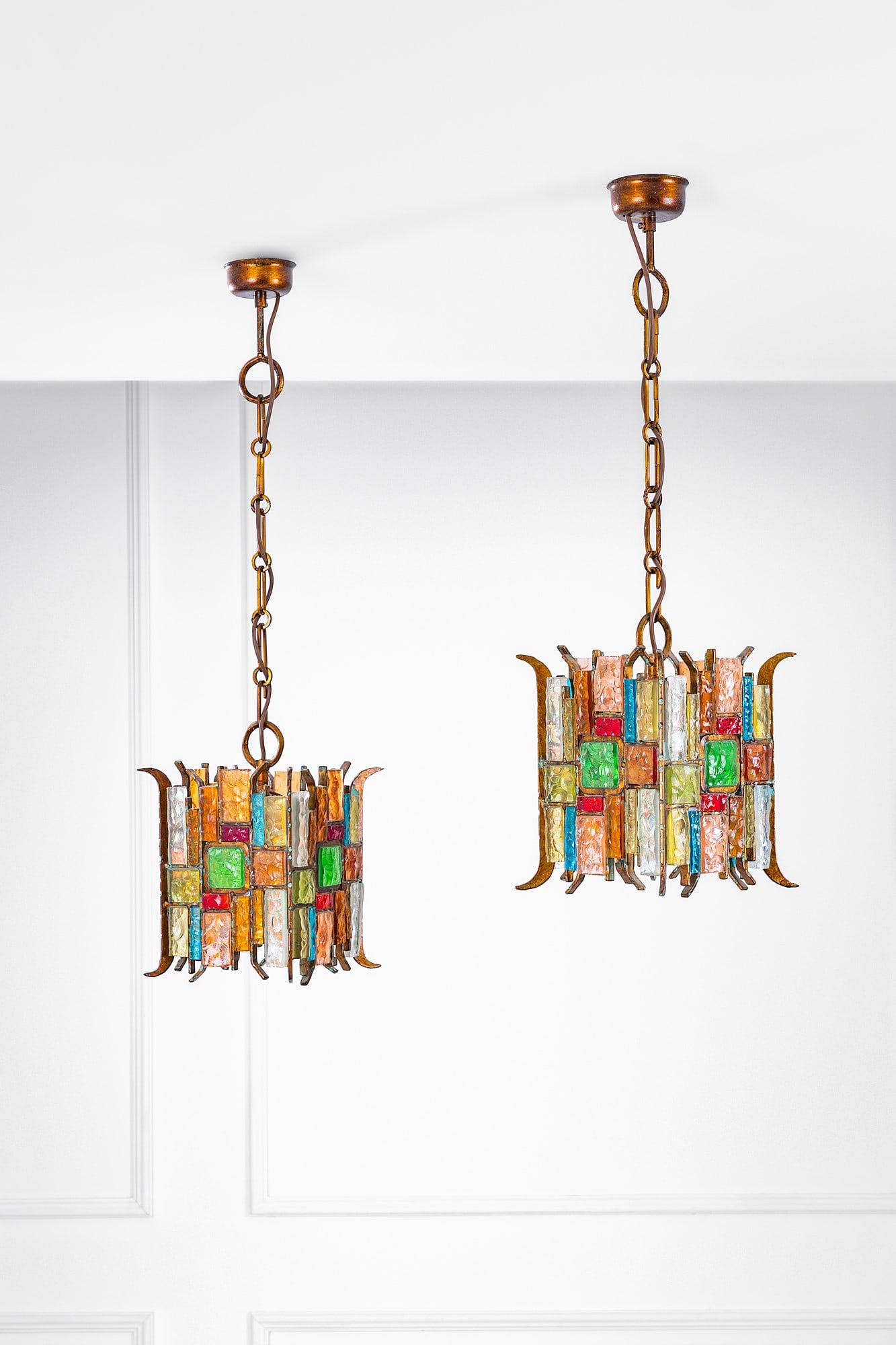 Poliarte. Due lampade a sospensione: Due lampade a sospensione Metallo con finitura rame, elementi in vetro colorato e trasparente lavorato a spacco. Prod. Poliarte, 1970 ca. cm 86x24x24, cm 98x24x24