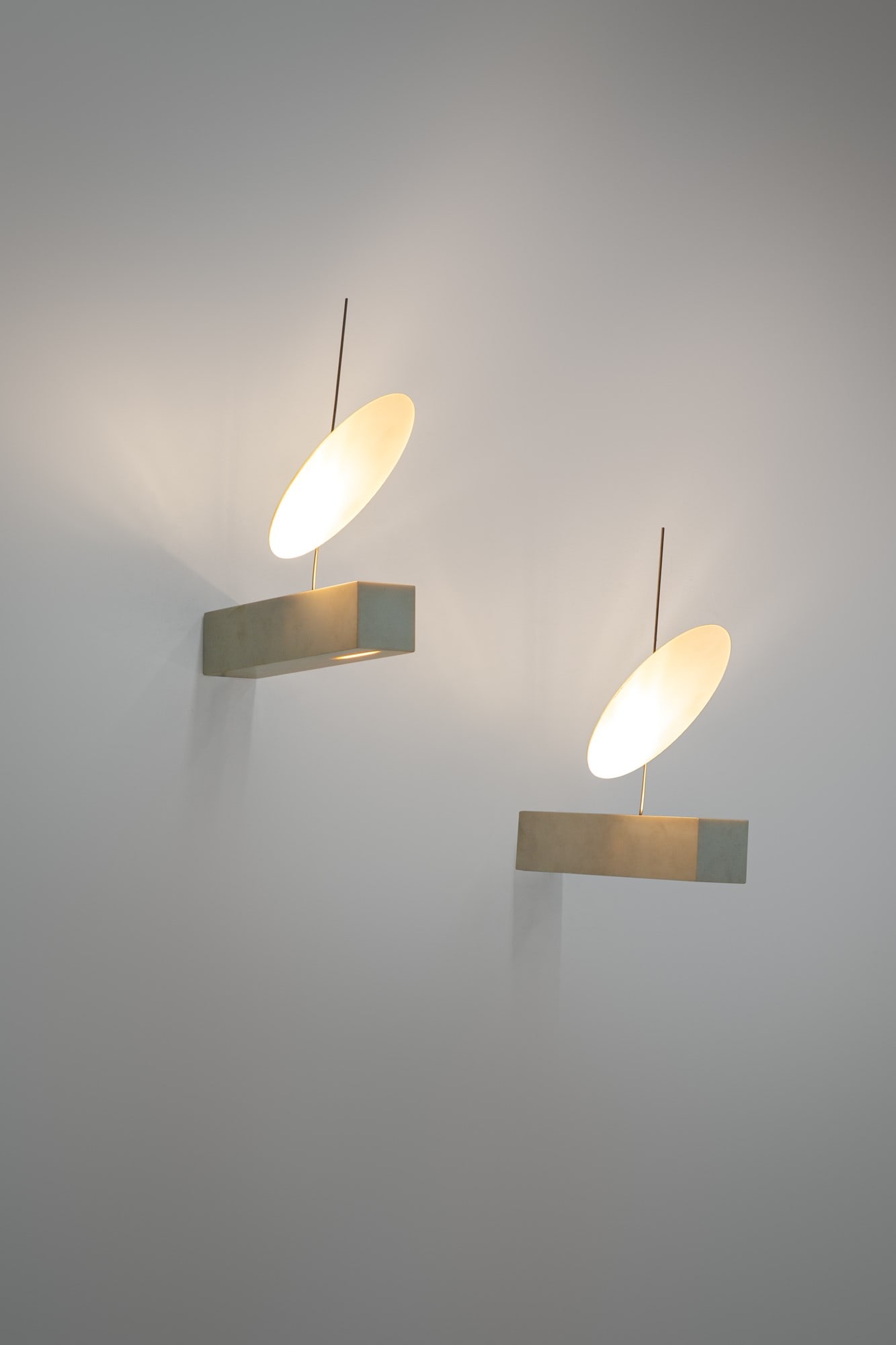 Ingo Maurer. Due lampade da parete mod. Zero One: Due lampade da parete mod. Zero One Corian bianco, specchio smerigliato. Prod. Ingo Maurer, 1990 ca. Etichetta di produzione. cm 5x5x27, diam. riflettore cm 17