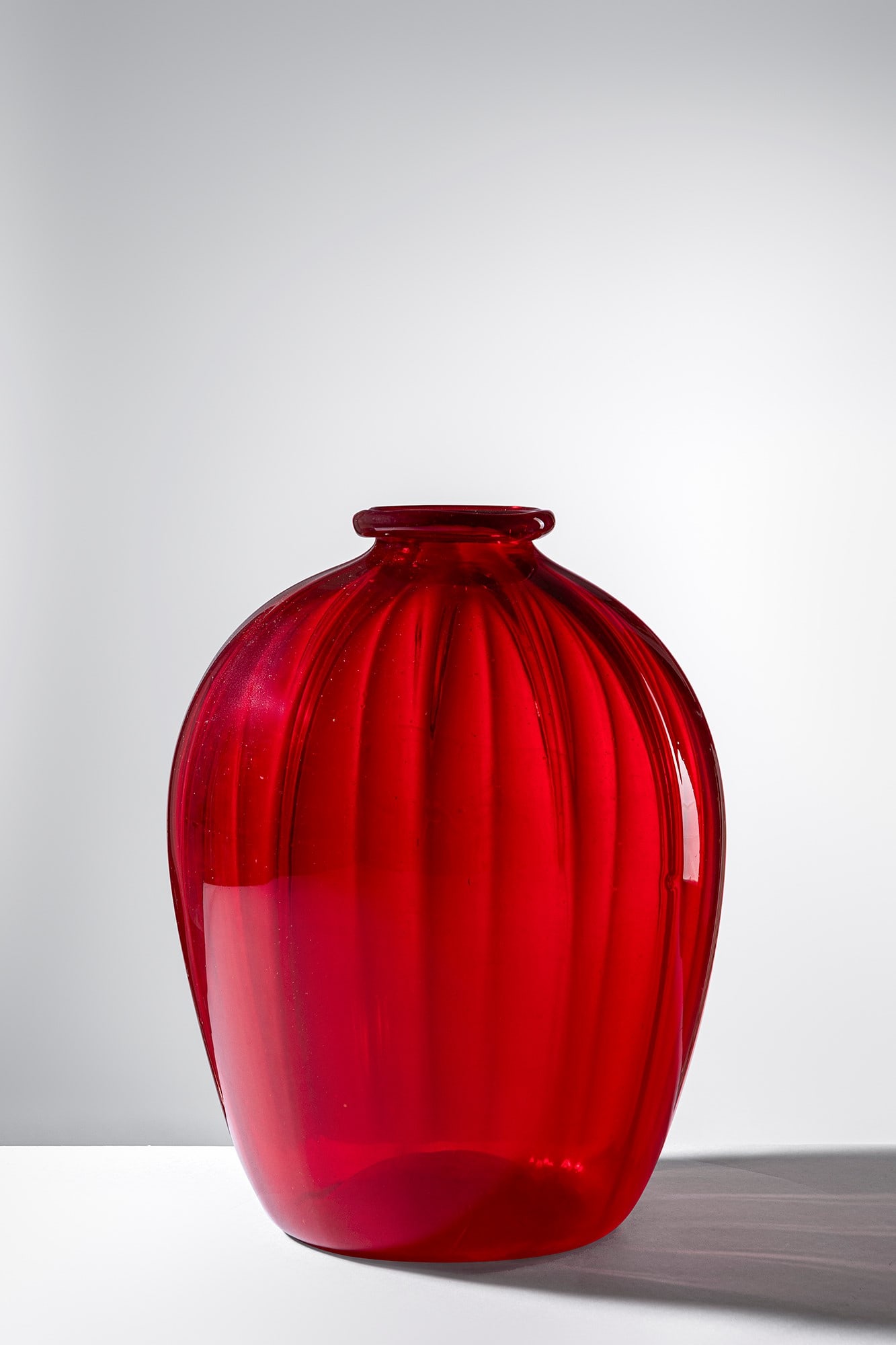Vittorio Zecchin. Vaso mod. 5300: Vaso mod. 5300 Vetro soffiato trasparente rosso rubino leggermente costolato. M.V.M. Cappellin & C. Murano. Disegno del 1922-1926, Il modello corrisponde al n. 5300. h cm 34, largh. cm 24 Bibliografia