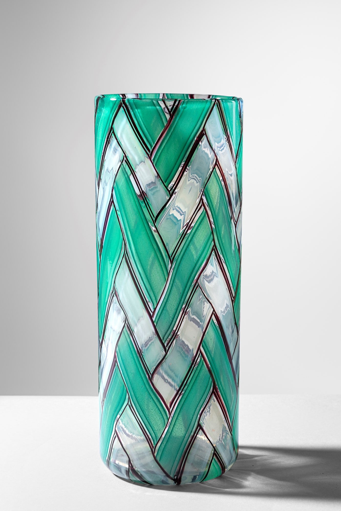 Ercole Barovier. Vaso della serie a Spina: Vaso della serie a Spina Tessuto vitreo costituito da tessere rettangolari opalino a bordi viola e tessere giada disposte a spina di pesce. Barovier & Toso, 1958. h cm 25, diam. cm 10 Bibliografia: A.