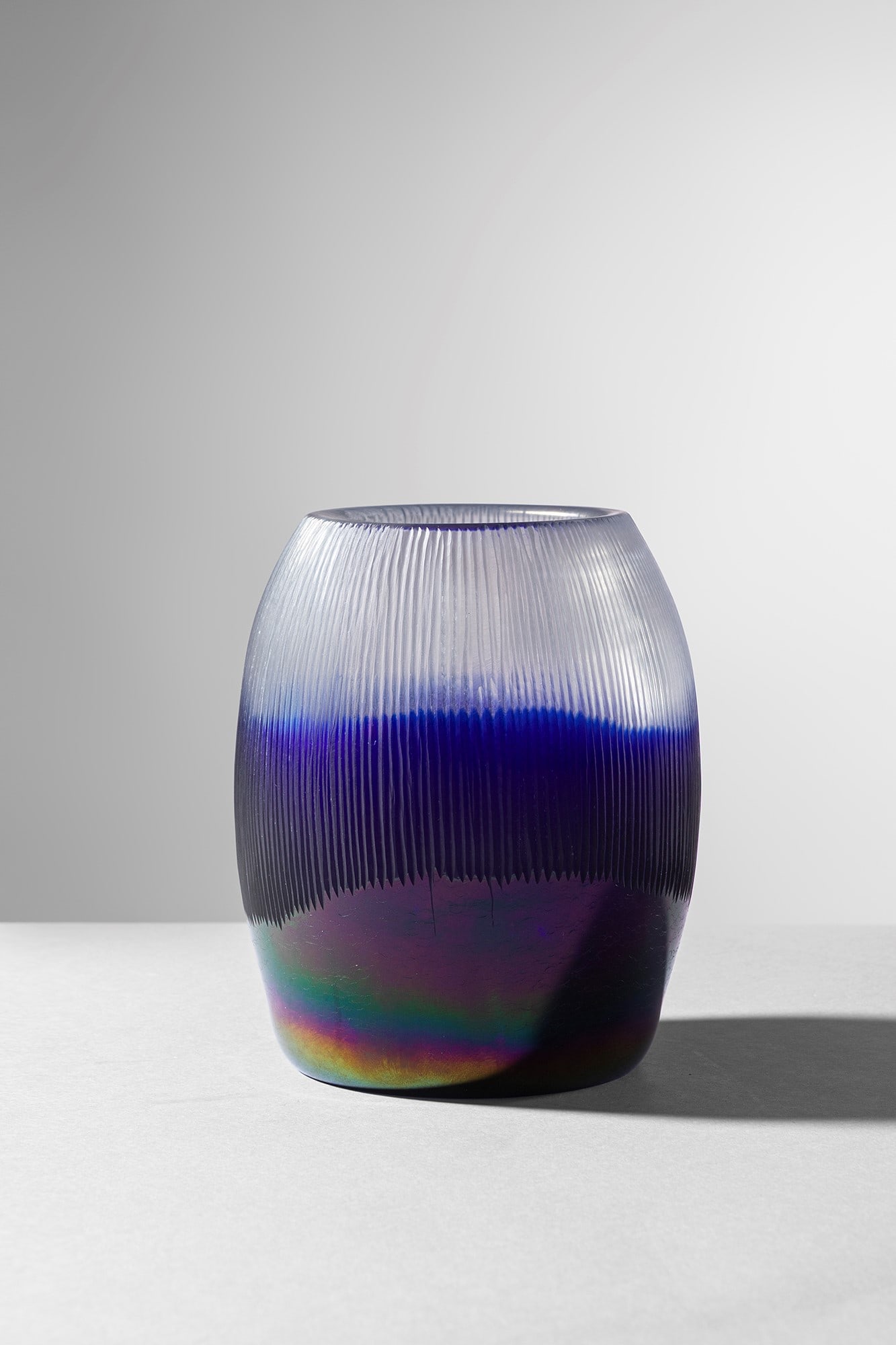 Thomas Stearns. Vaso della serie Nebbia di Luna mod. 8625: Vaso della serie Nebbia di Luna mod. 8625 Vetro trasparente incolore e vetro opaco indaco con tratto superiore rifinito con fitte incisioni verticali. Base di forte spessore e fortemente iridata.