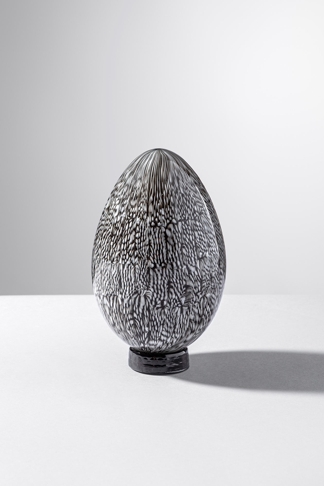 Paolo Venini. Uovo: Uovo Vetro a murrine nere e lattimo con piedistallo in pasta vitrea nera. Venini, 1963-1964. Firma incisa a punta Venini Italia. h cm 13, larg. cm 8 Bibliografia: Alessandro Bettagno (a cura di), Gli 