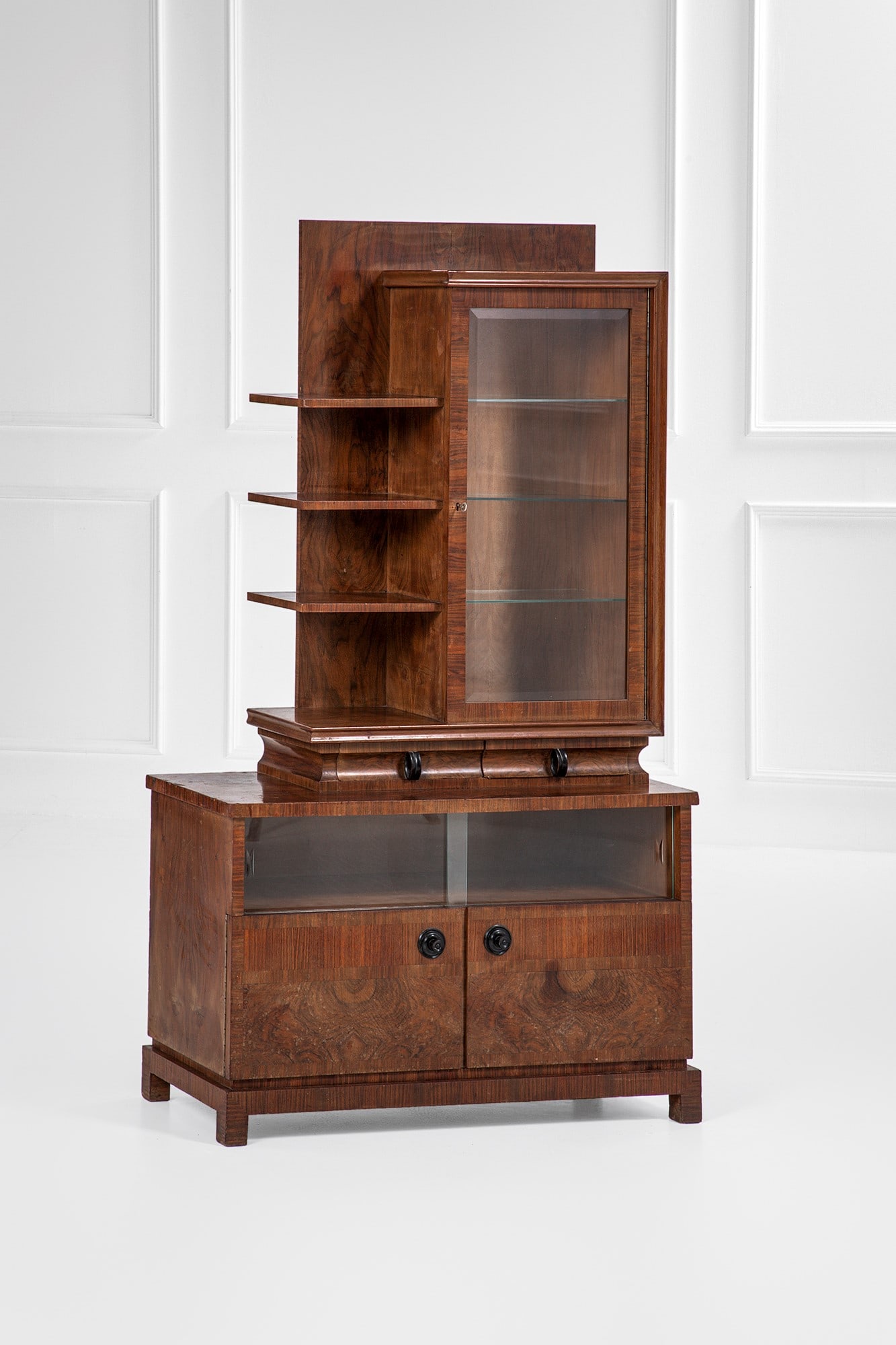 Cabinet con soprastante étagère e vetrina: Cabinet con soprastante étagère e vetrina Legno impiallacciato in radica, legno ebanizzato, legno impiallacciato, vetro trasparente satinato. 1930 ca. cm 180x102x44