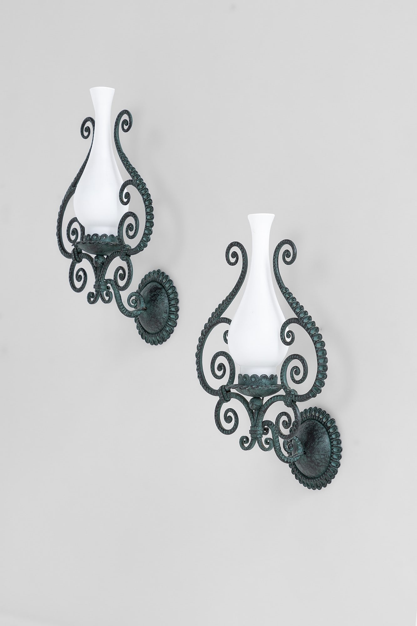 Carlo Rizzarda (attr.). Due lampade da parete: Due lampade da parete Ferro battuto sagomato a motivi di volute, vetro opalino satinato. 1930 ca. cm 32x23x14