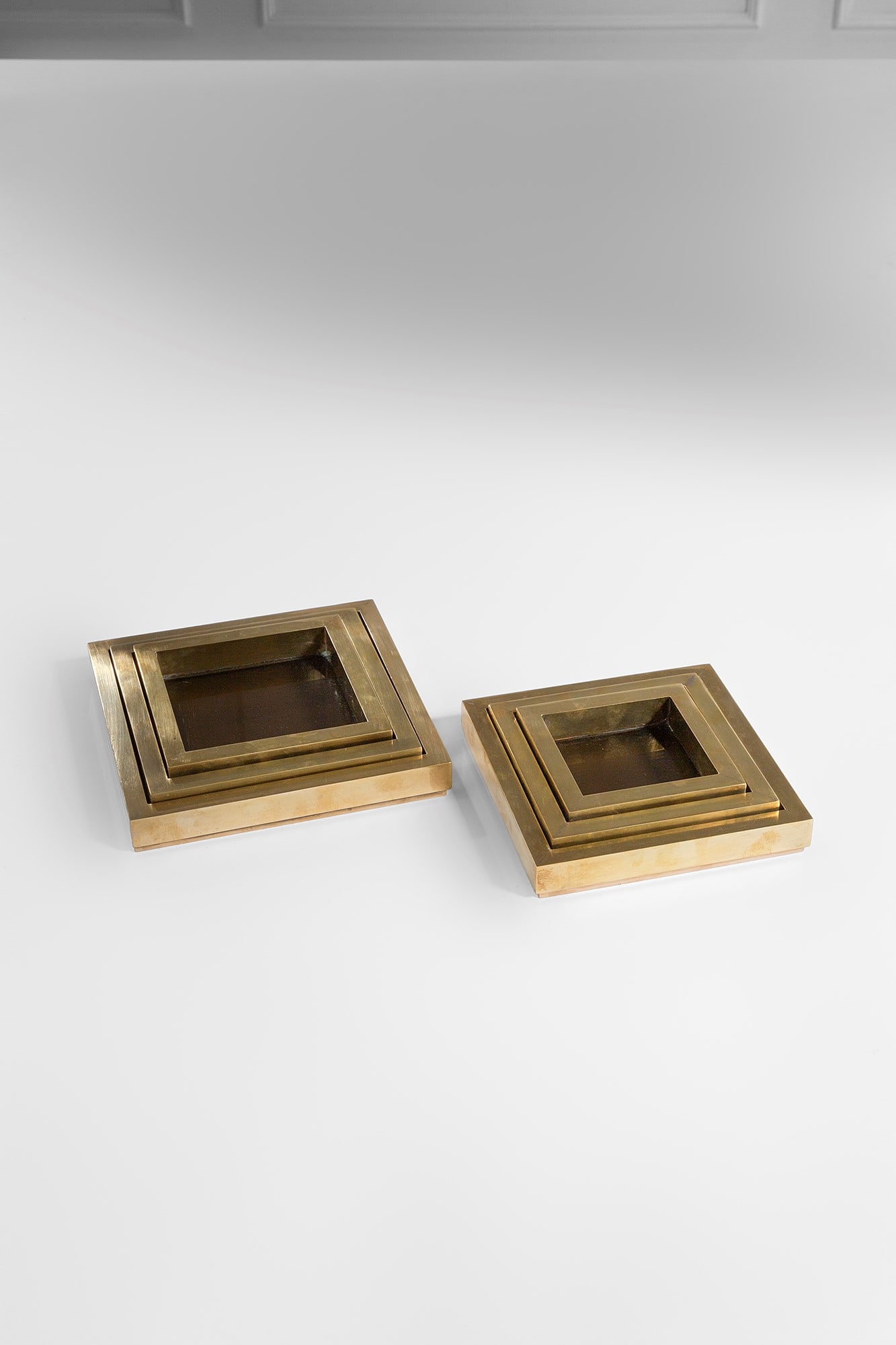 Set di sei centrotavola impilabili: Set di sei centrotavola impilabili Ottone, vetro fumè. 1970 ca. cm 5x24x24; cm 5x20x20