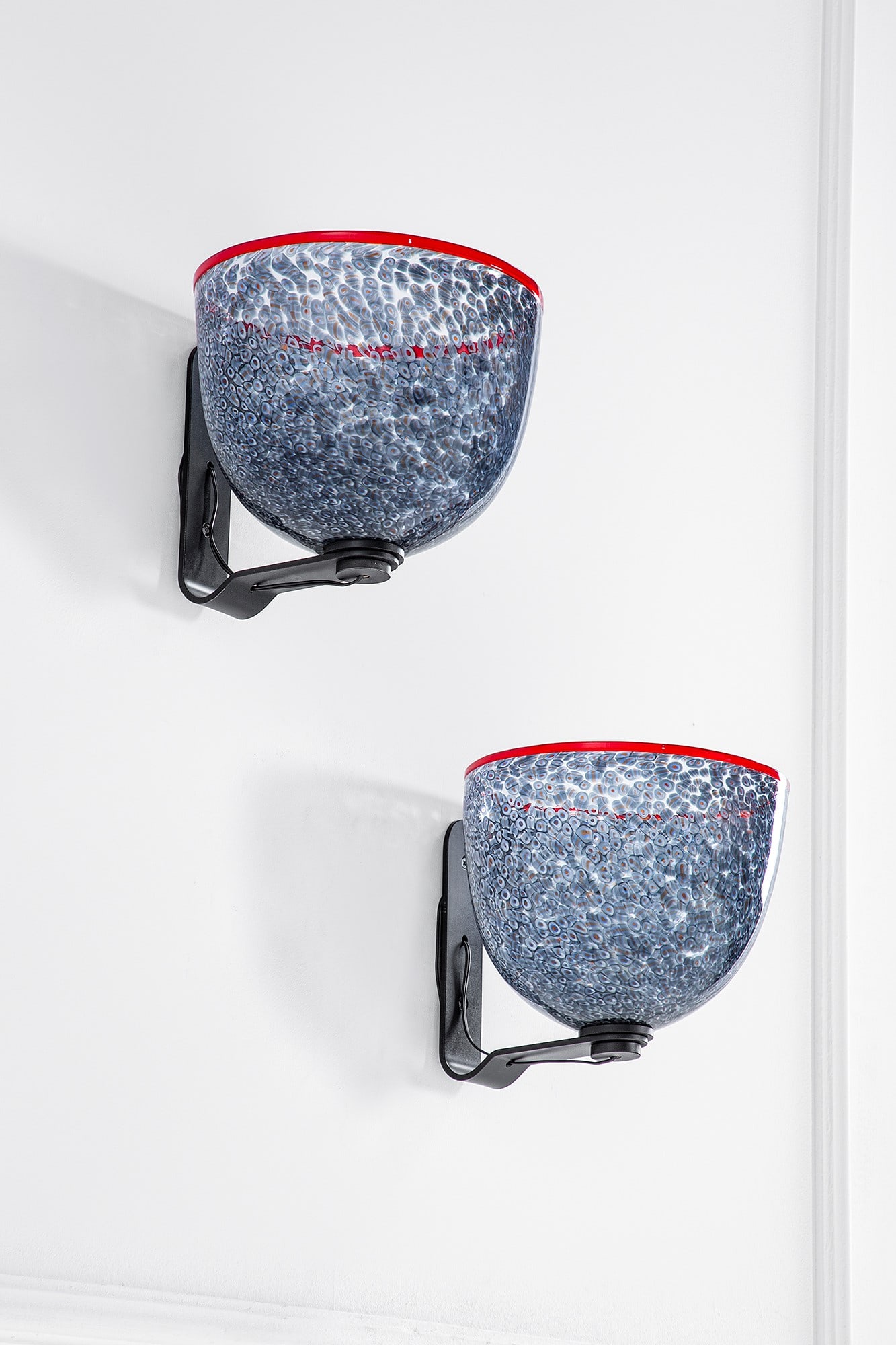 Gae Aulenti. Due lampade da parete della serie Neverrino: Due lampade da parete della serie Neverrino Metallo verniciato, vetro a murrine. Prod. Vistosi, 1975 ca. Firma incisa Vistosi cm 25x26x29