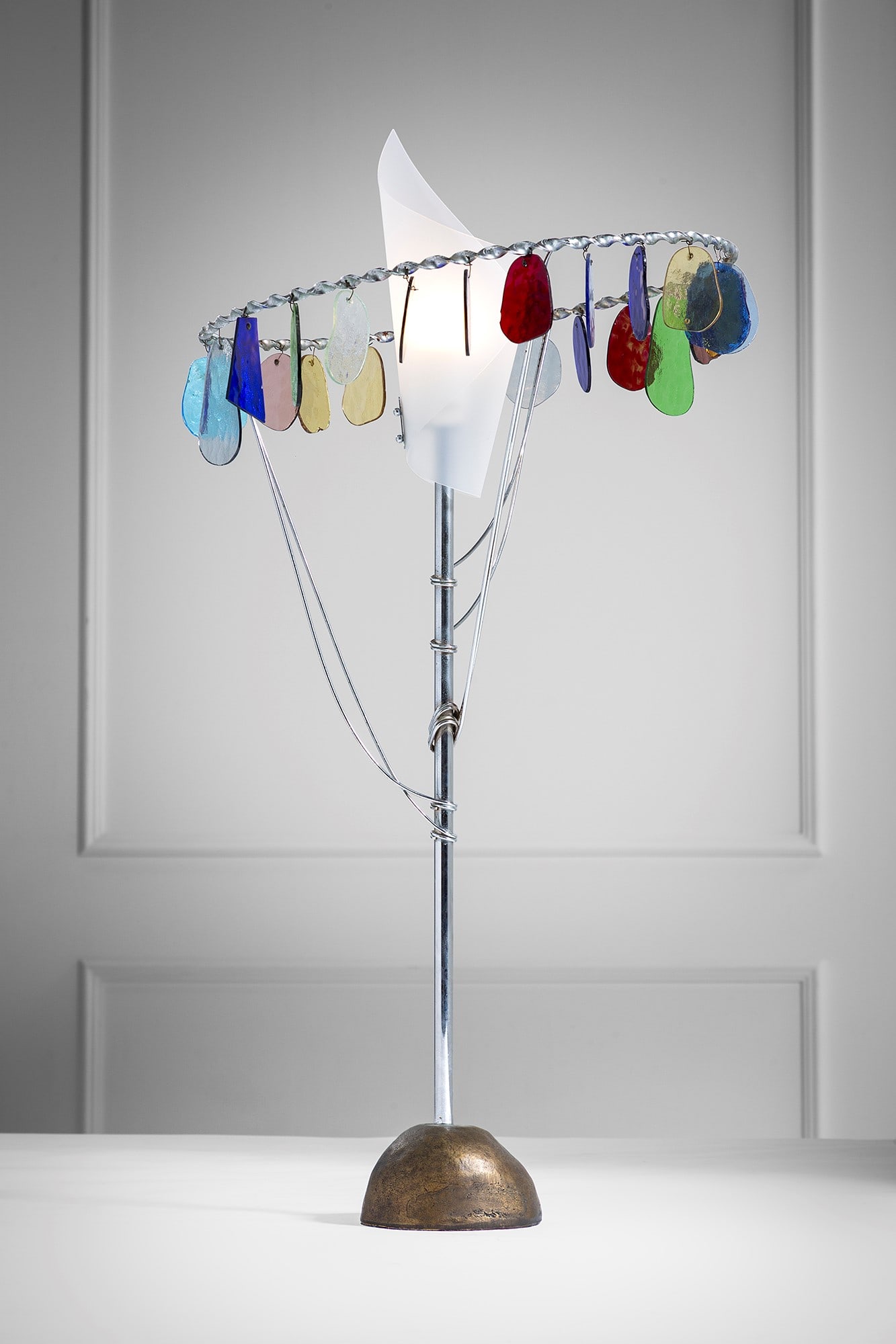 Toni Cordero. Lampada da tavolo mod. Sibari: Lampada da tavolo mod. Sibari Fusione di bronzo, acciaio cromato, elementi in vetro colorato, polietilene opalino. Prod. Artemide, 1990 ca. Etichetta del produttore. h cm 90, diam. cm 46