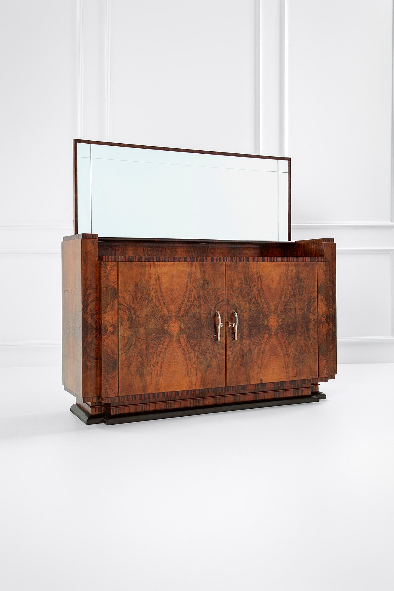 Gaetano Borsani (attr.). Grande credenza con specchiera: Grande credenza con specchiera Legno impiallacciato in radica, legno impiallacciato in varie essenze, legno tinto, vetro specchiato, metallo nichelato, bachelite. 1930 ca. cm 170x176x50