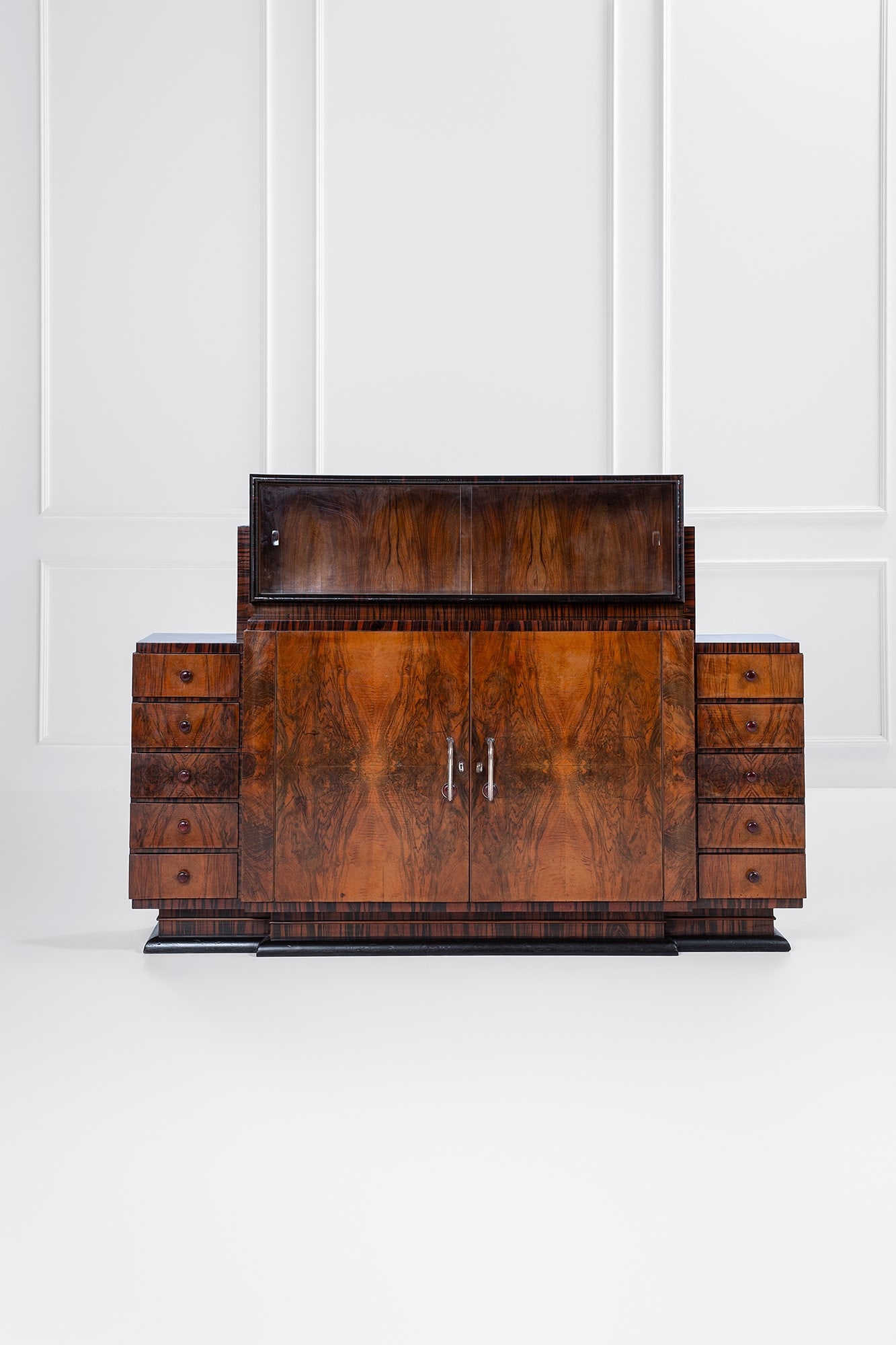 Gaetano Borsani (attr.). Grande credenza con alzata: Grande credenza con alzata Legno impiallacciato in radica, legno impiallacciato in varie essenze, legno tinto, vetro trasparente, metallo nichelato, bachelite. 1930 ca. cm 143x200x52