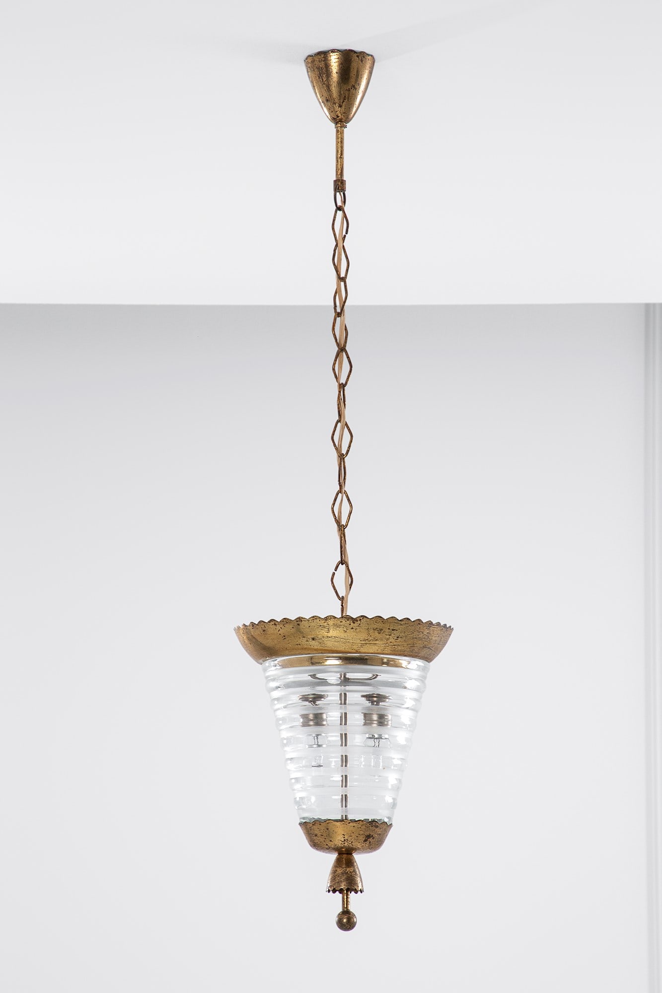 Pietro Chiesa, nel gusto di. Lampada a sospensione: Lampada a sospensione Ottone lucido, vetro costolato trasparente con fasce satinate. 1930 ca. h cm 103, diam. cm 27