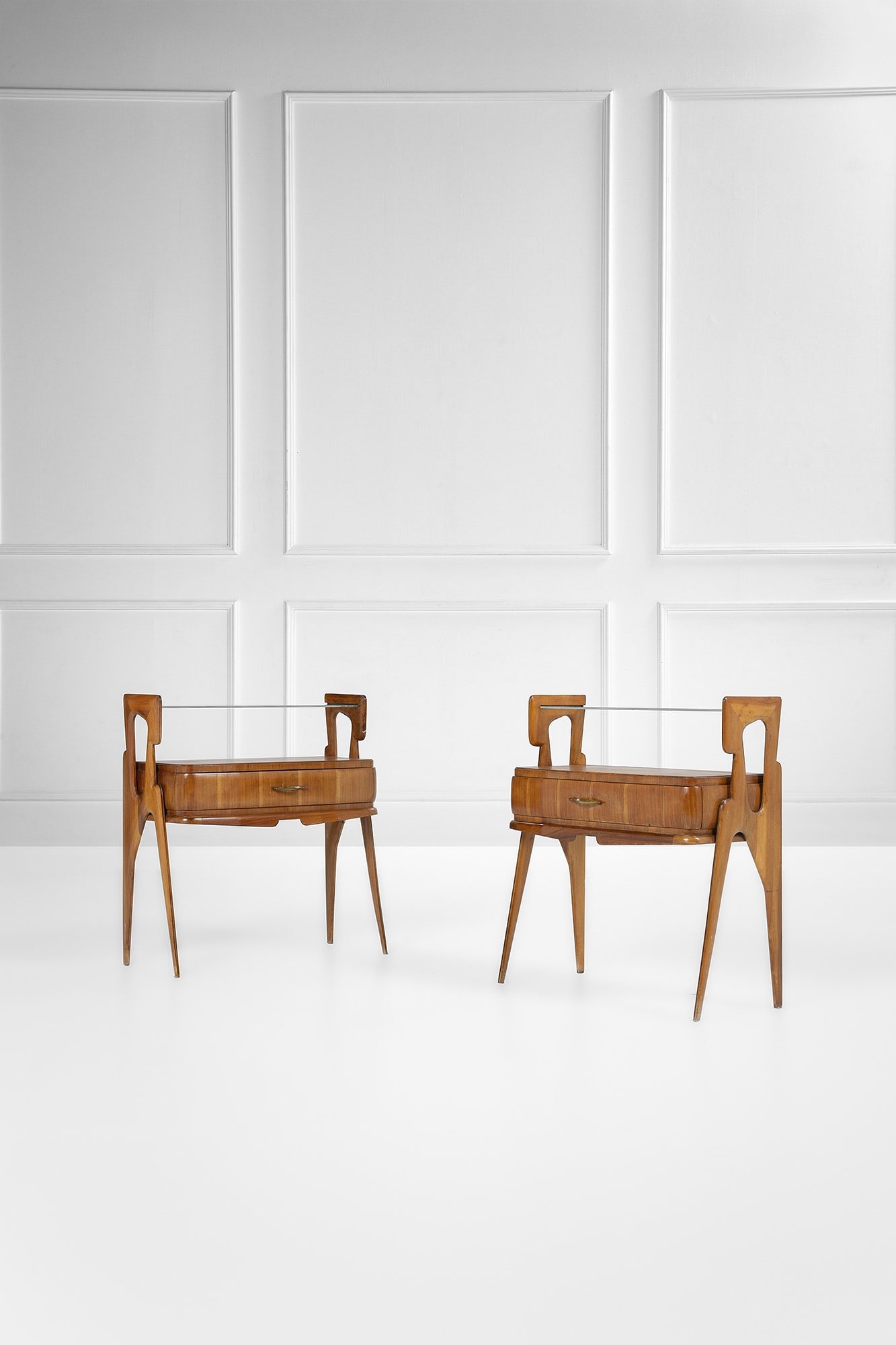Due comodini: Due comodini Legno sagomato, legno impiallacciato, ottone, vetro trasparente. 1950 ca. cm 67x61x30