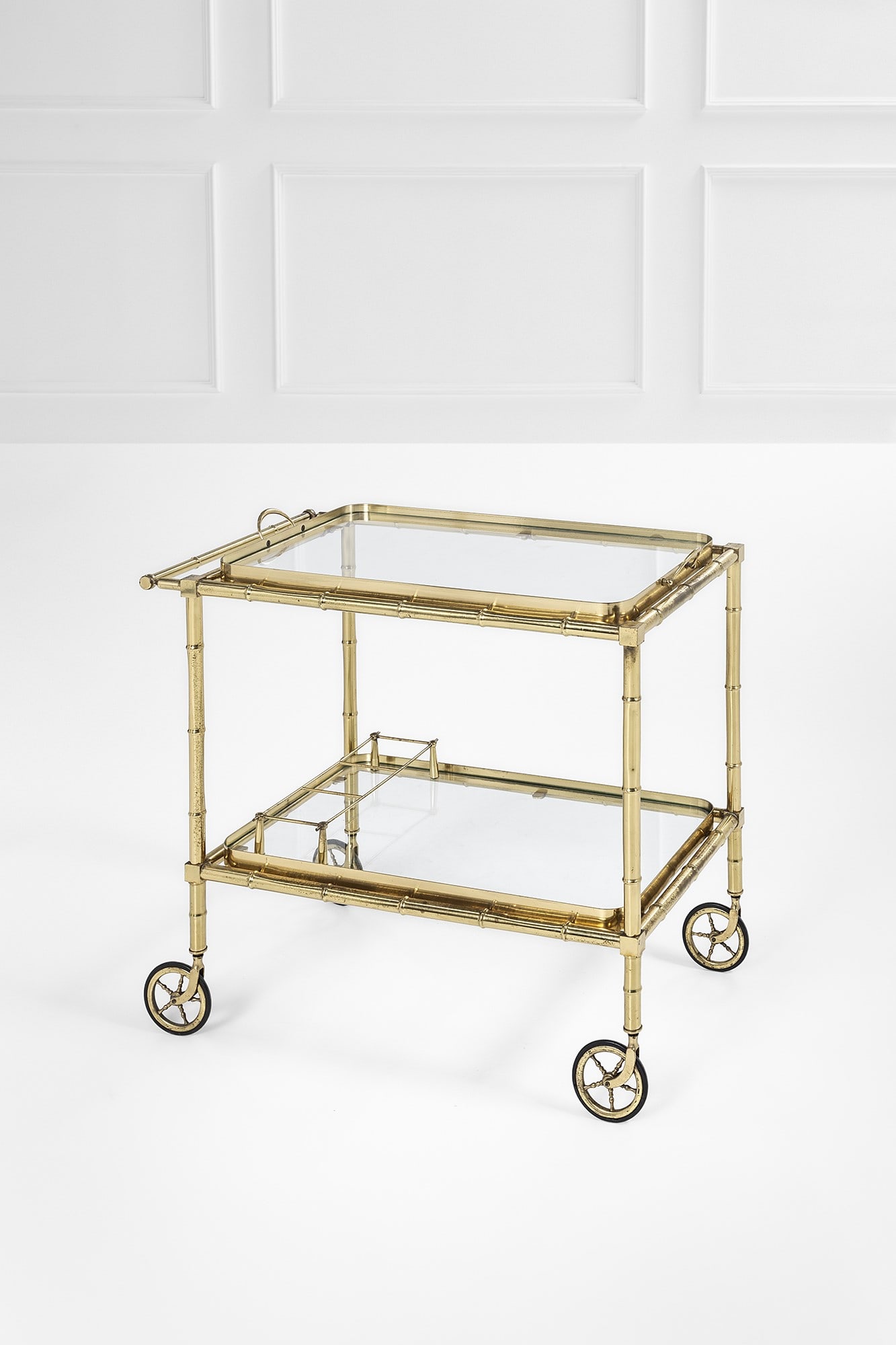 Maison Jansen (attr.). Carrello di servizio con vassoio e portabottiglie: Carrello di servizio con vassoio e portabottiglie Elementi in ottone lucido a imitazione del bambù, cristallo. 1970 ca. cm 71x42x78