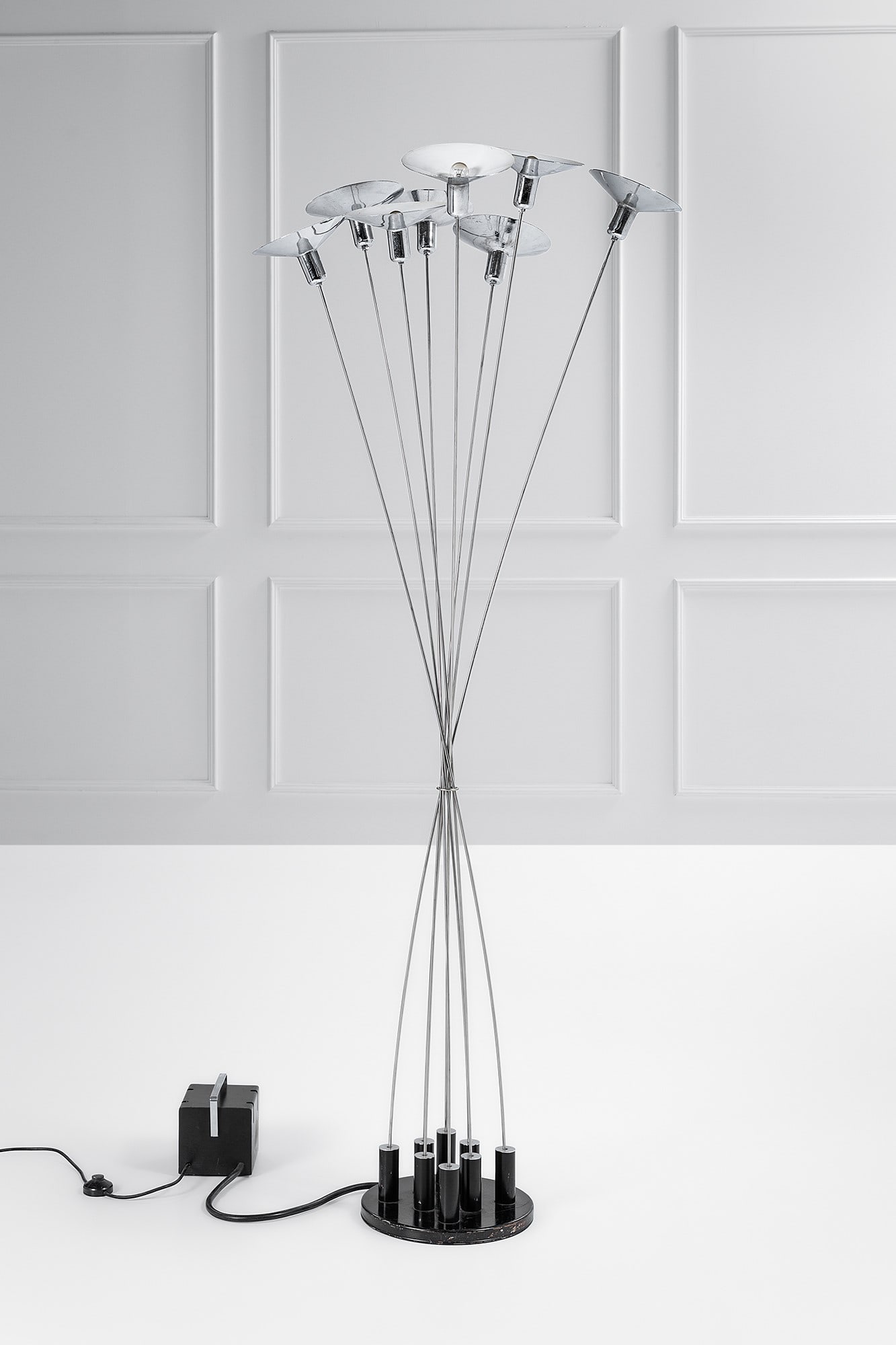 Sergio Moscheni. Lampada terra mod. Calle: Lampada terra mod. Calle Metallo cromato, metallo verniciato. La lampada è concepita per funzionare con uno o più steli fino ad un massimo di 12. L'impianto elettrico a basso voltaggio conduce la