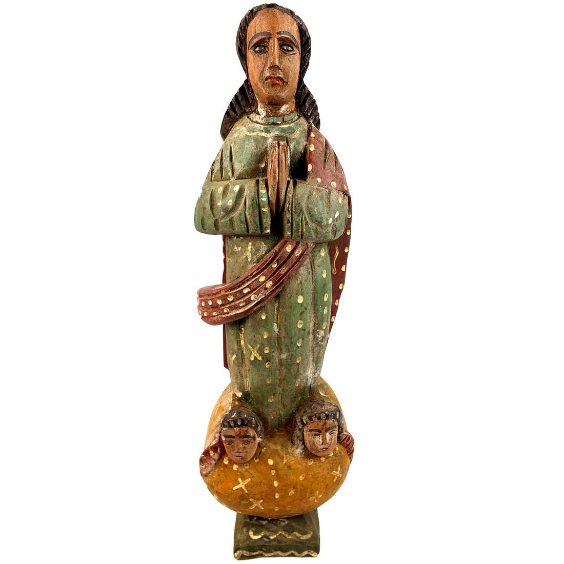 Santos Figure: 19/20th Century South American School Polychrome Wood Santos Figure. Depicts an idol in traditional garments standing above angel figural heads. Measures 15" x 4-3/4". Condition: Rubbing to the surfac