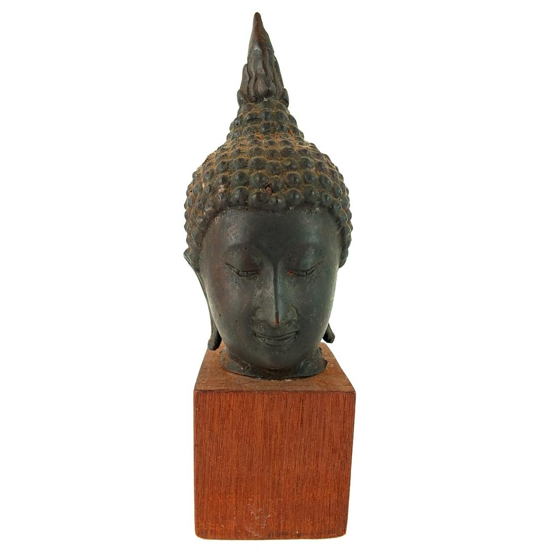 Buddha Head: Antique Thai Bronze Sculpture of a Buddha Head Presented on Wooden Plinth Base. Overall measures 10-1/4" H. Head measures 7-1/2" x 2-3/4" x 3-1/2". Condition: Rubbing otherwise good condition. Estimat