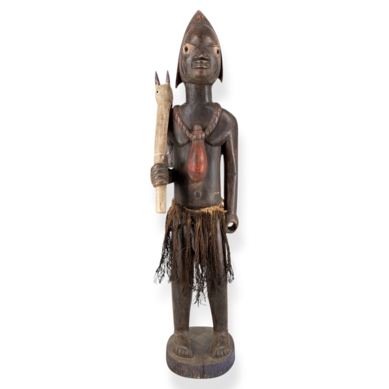 African Possibly Fang Carved Wood Figure 46": Vintage African Possibly Fang Carved Wood Figure "Medicine Man"? Wearing a raffia skirt, a jar around his neck and holding a figural scepter. Unsigned. Measures 46" H x 11" W. Condition: Wear and rubb