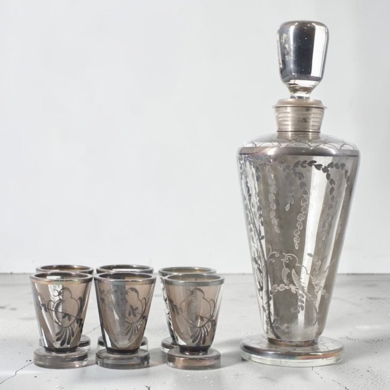 Art Deco 800 Silver Overlay Glass Cordial Set: 7 Piece Art Deco 800 Silver Overlay Glass Cordial Set. Includes decanter 10" and 6 glasses 2-1/2". Stamped 800 on collar of decanter. Condition: 1 chip on foot of 1 glass, wear to silver, stopper