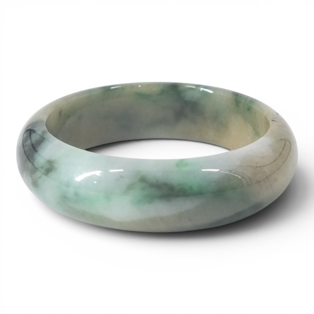 Chinese Jadeite Bangle: Chinese Jadeite Jade Bangle. Mottled hues of mixed green and yellow. Unsigned. Measures 2-1/4" at opening x 3/4" thick, weighs approx. 91 grams. Condition: Good condition. Estimate 400 - 600 Domestic