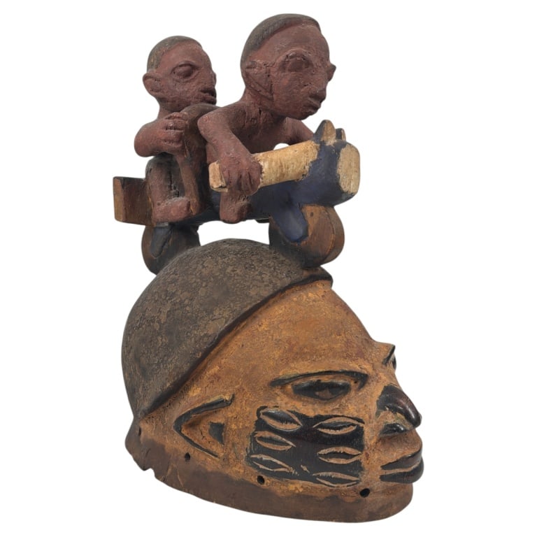Vintage Nigerian Yoruba Carved Wood Headpiece: Mid 20th C Nigerian Yoruba Polychrome Carved Wood Headpiece. Helmet style with figures riding a bike. Unsigned. Measures 14" H x 11" x 7" . Condition: Wear, rubbing condition consistent with age. Esti