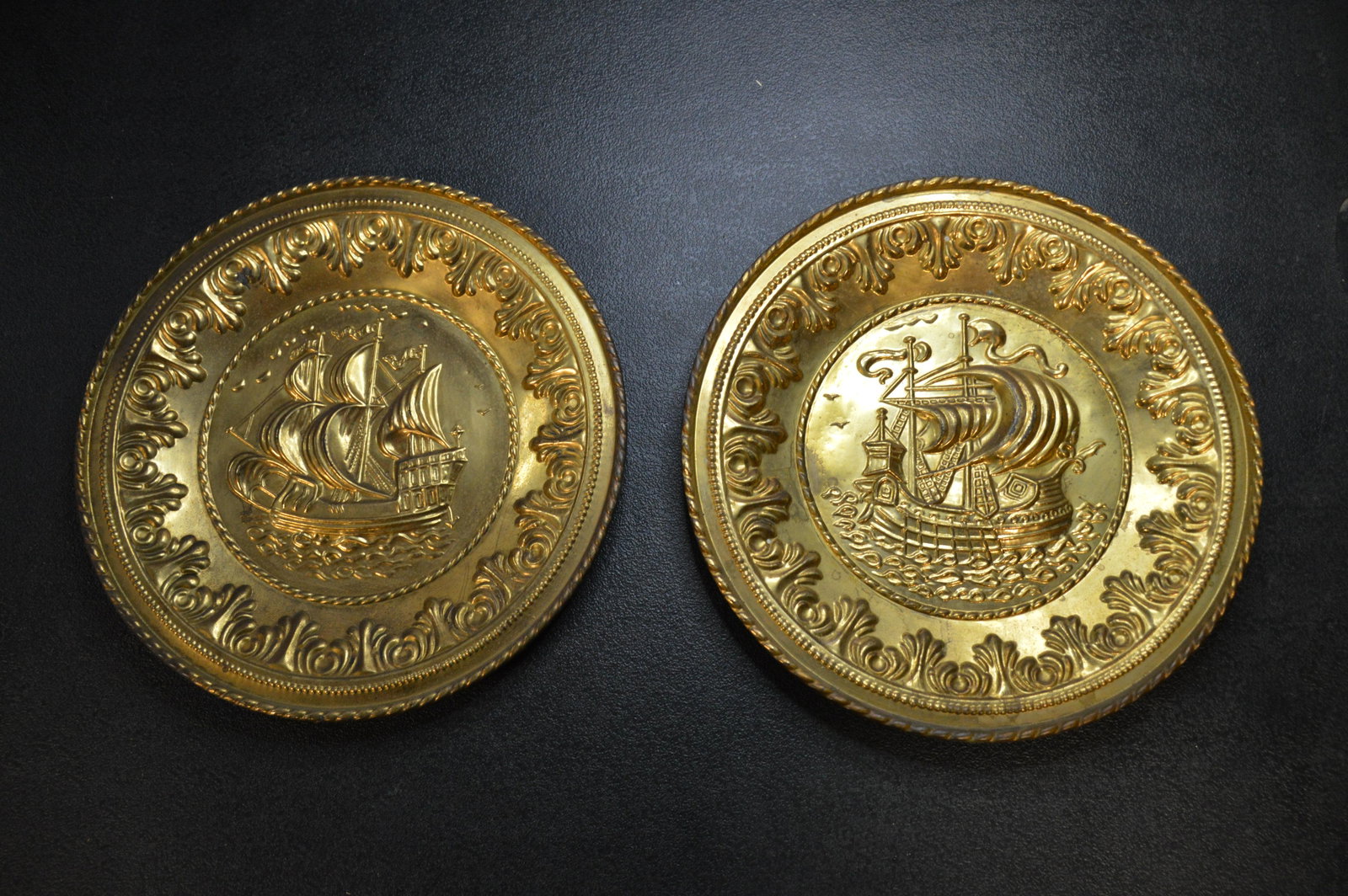 2 Gold Colored Ship Metal Trays.: No information on these except They are both in great shape and have a hook on the back to hang them on the wall.