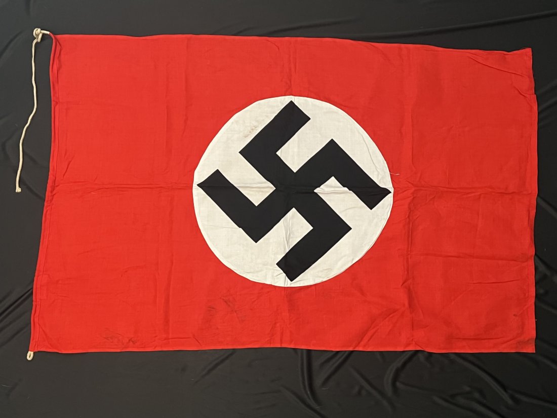 Original Third Reich National Double Sided Flag With: The flag has a tunnel at one end with maker’s tag sewn on and reinforced threaded corners at the other end. Tag is marked “Flaggenfabrik, Anfelstadt & Hornung, Hamburg + Altona”. Nice bright red