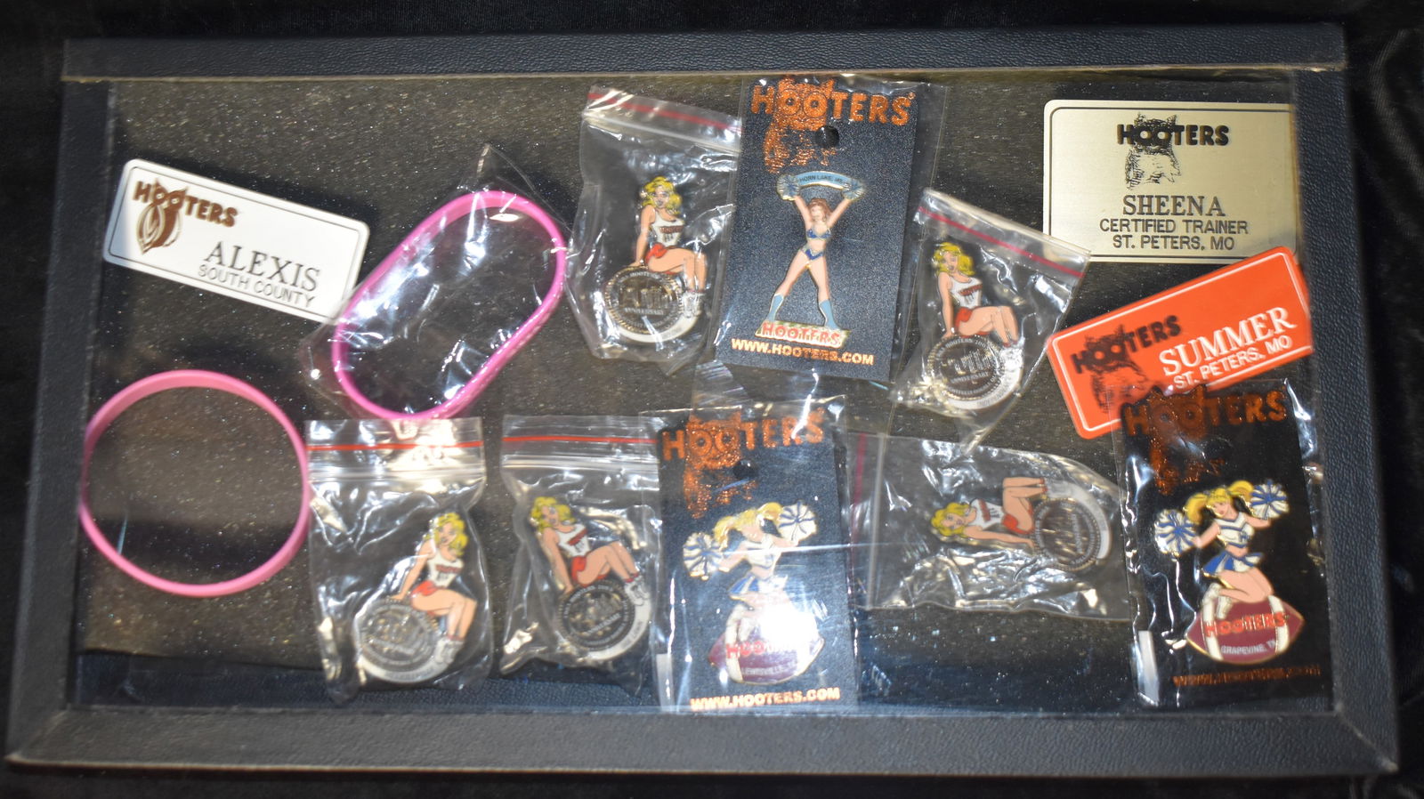 Hooters Collection w/ Display Case - Pins, Bracelets and Name Tags: Hooters Collection - Pins, Tokens, Key Chains, Bracelets and Name Tags. Looks like mostly early 2000's Hooters memorabilia. Comes with a display case they have been kept in. Case measures 8 2/8" by 14