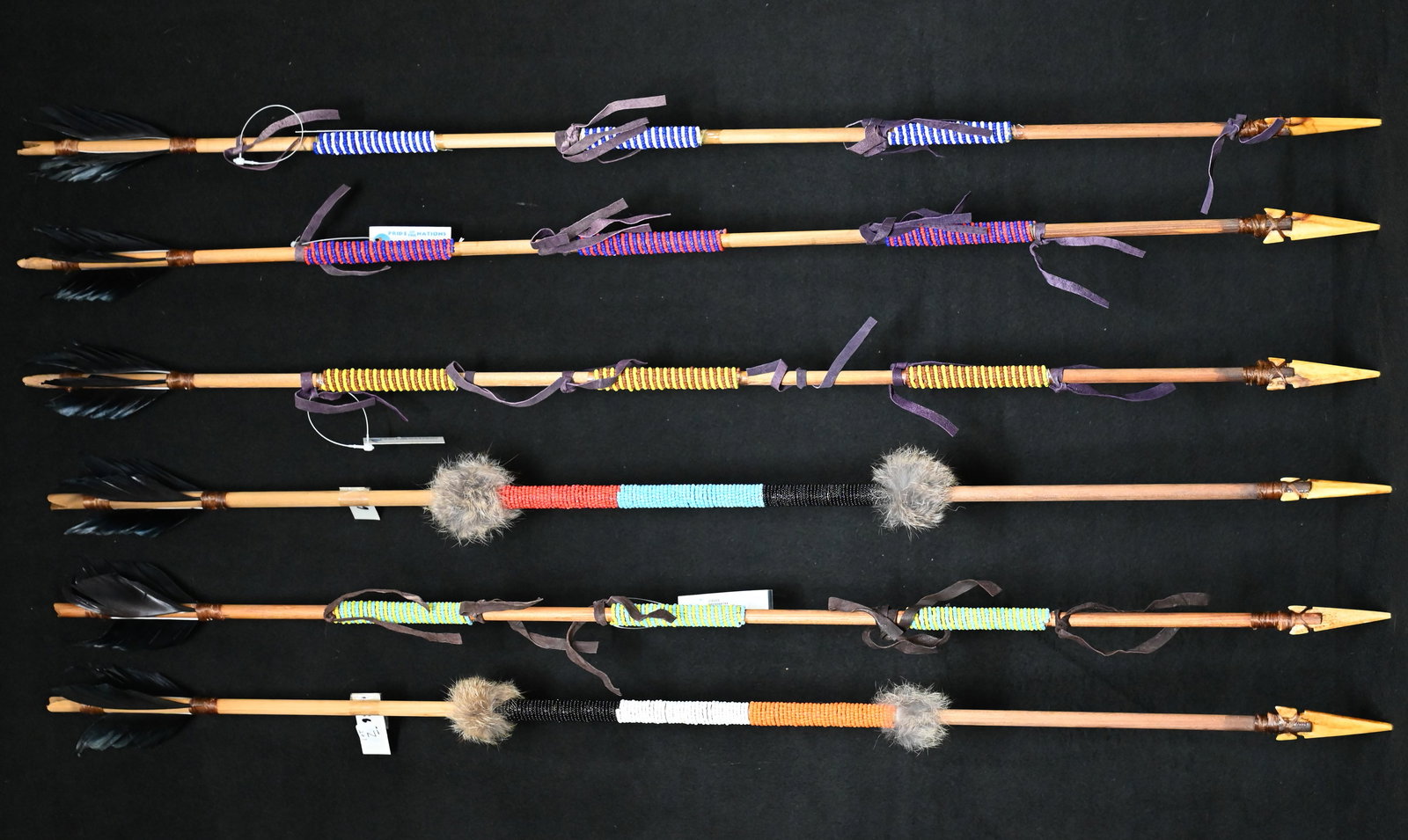 6 Hand Made Wood 34" Arrows Made by Native Americans: 6 Hand Made Wood 34" Wood Arrows. Bone arrow points attached with sinew to the wood shaft that is decorated with beadwork. The crow feather fletching is attached with sinew and some have rabbit fur fo