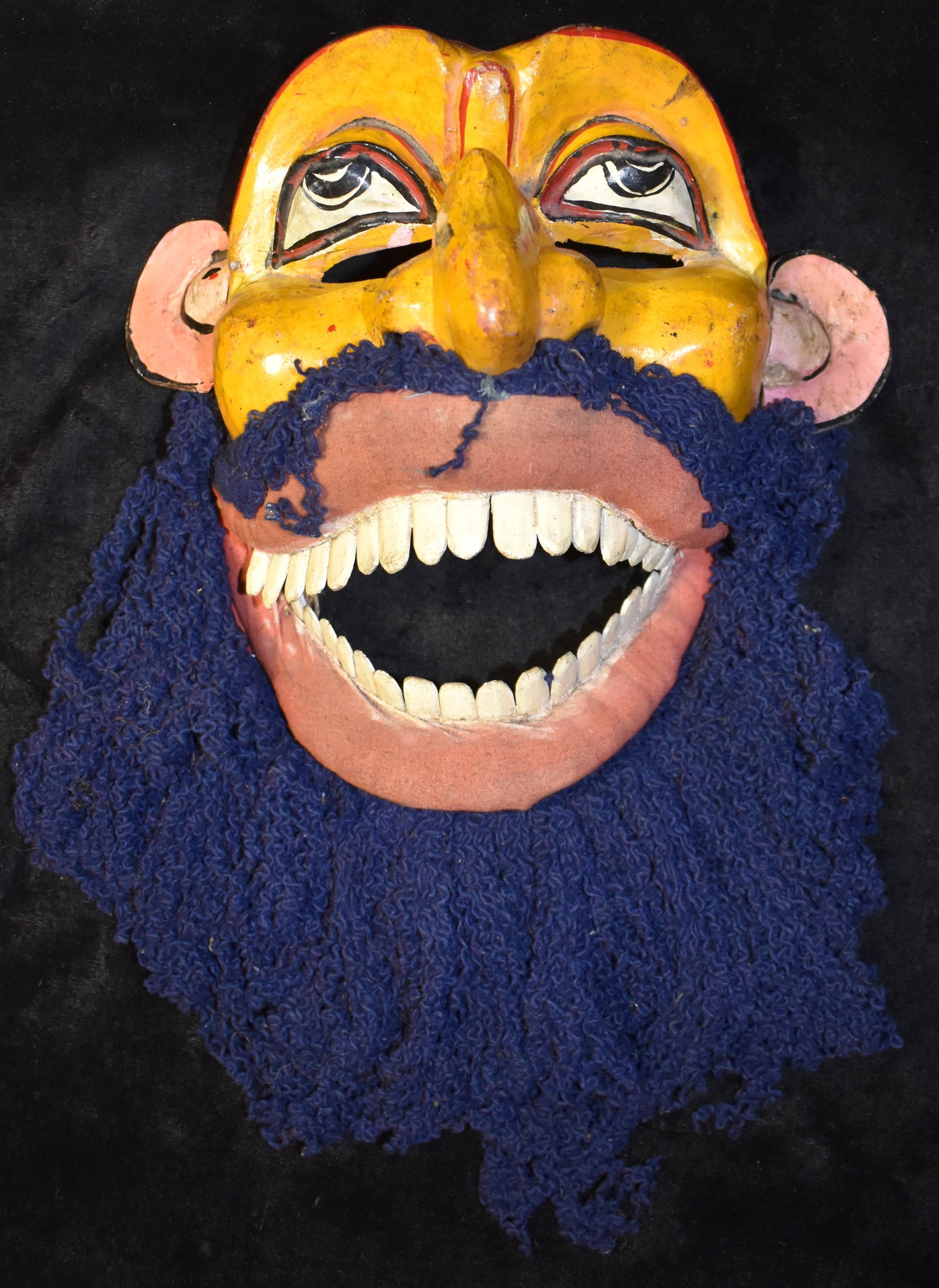 Yellow Polychrome Sri Lanka Kolam Mask - Mid Century or Older: Mid Century Kolam Mask from Sri Lanka. Excellent condition polychrome painted mask hand carved from wood with cloth lips and beard. The mouth is hinged allowing it to be moved up and down mimicking sp
