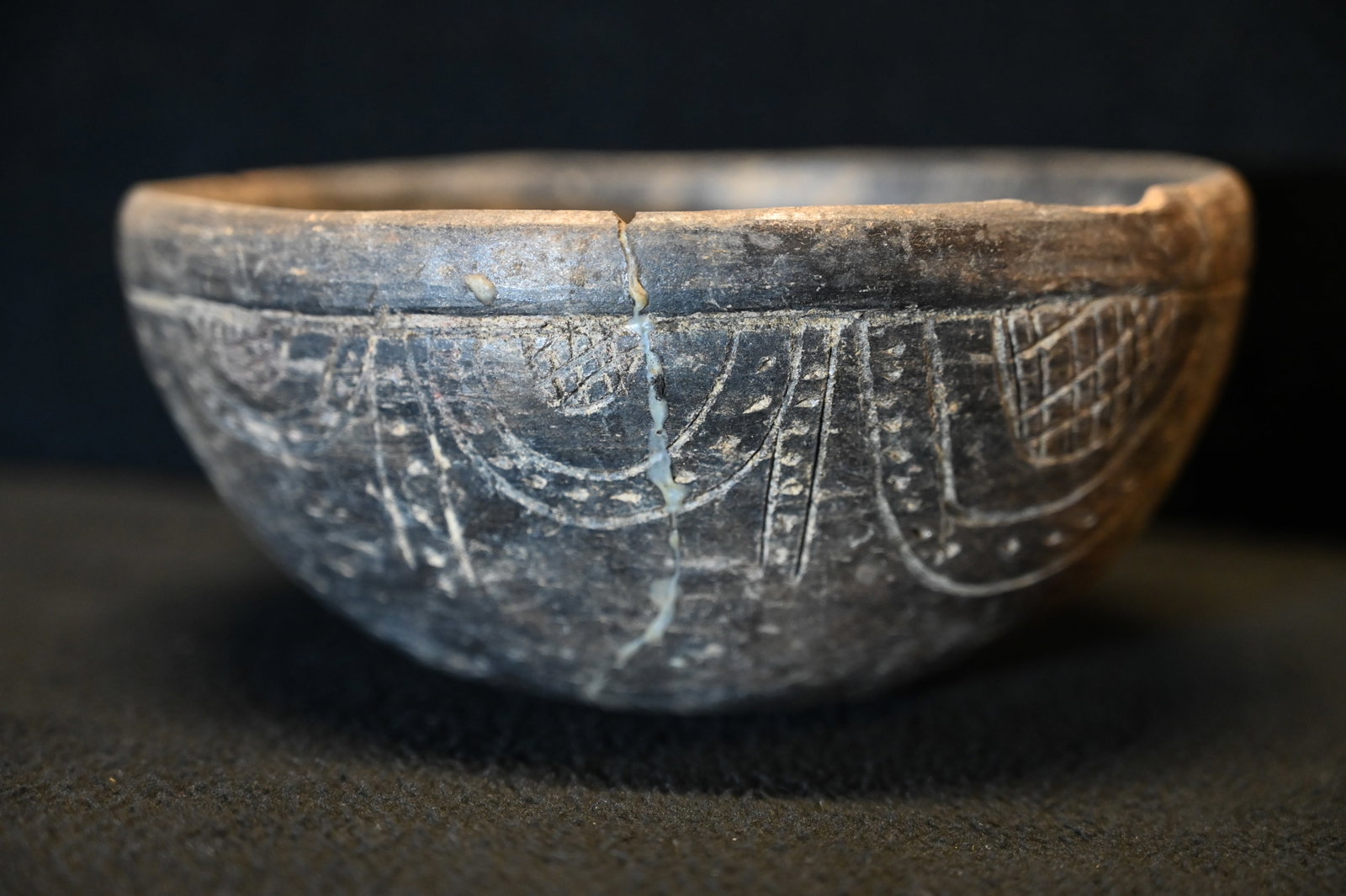 Pre-Columbian Incised Black ware Bowl: From the Mississippian Caddo Culture. These bowls were used for both every day and ceremonial purposes. Features incised geometric patterns. Was cracked into 3 pieces and repaired. Has a small area of