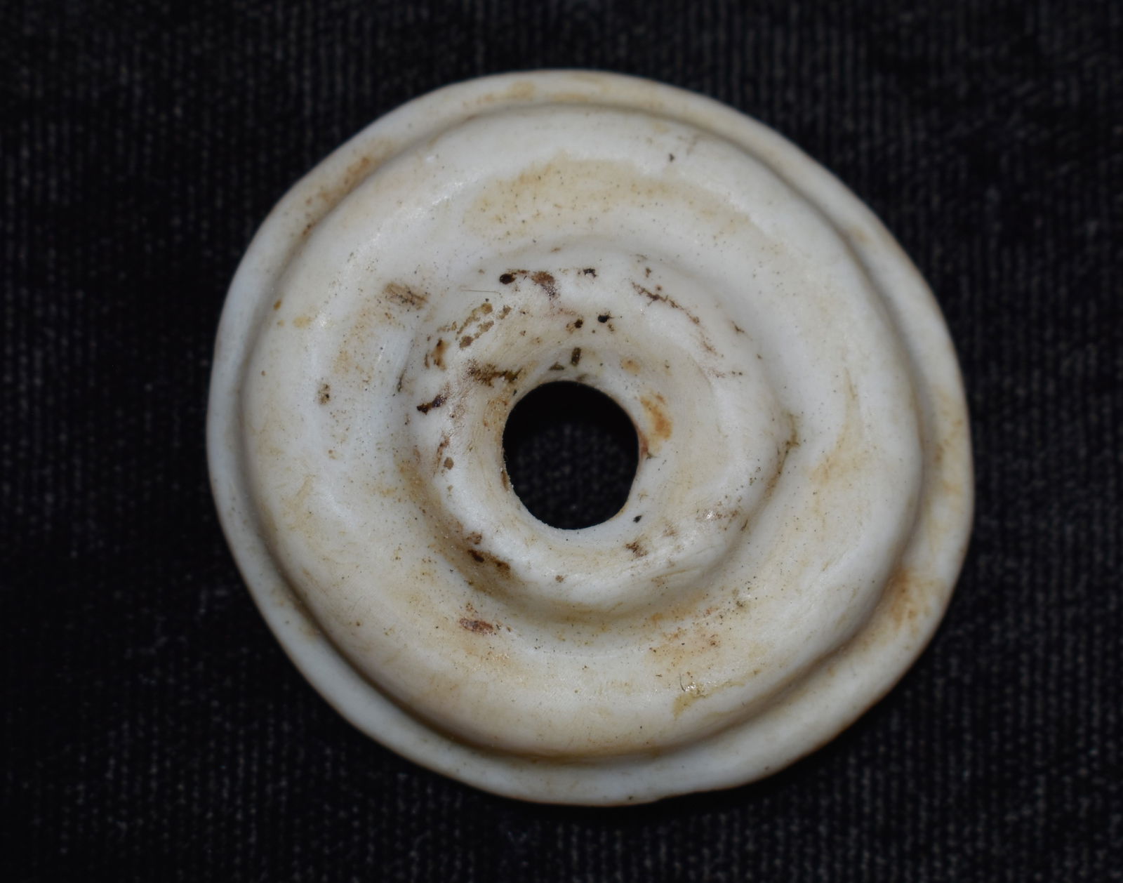 Pre-Columbian Mayan Ear Spool: Pre-Columbian Mayan Ear Spool. Appears to be made from shell or bone. Measures 1 1/2" diameter approximately.