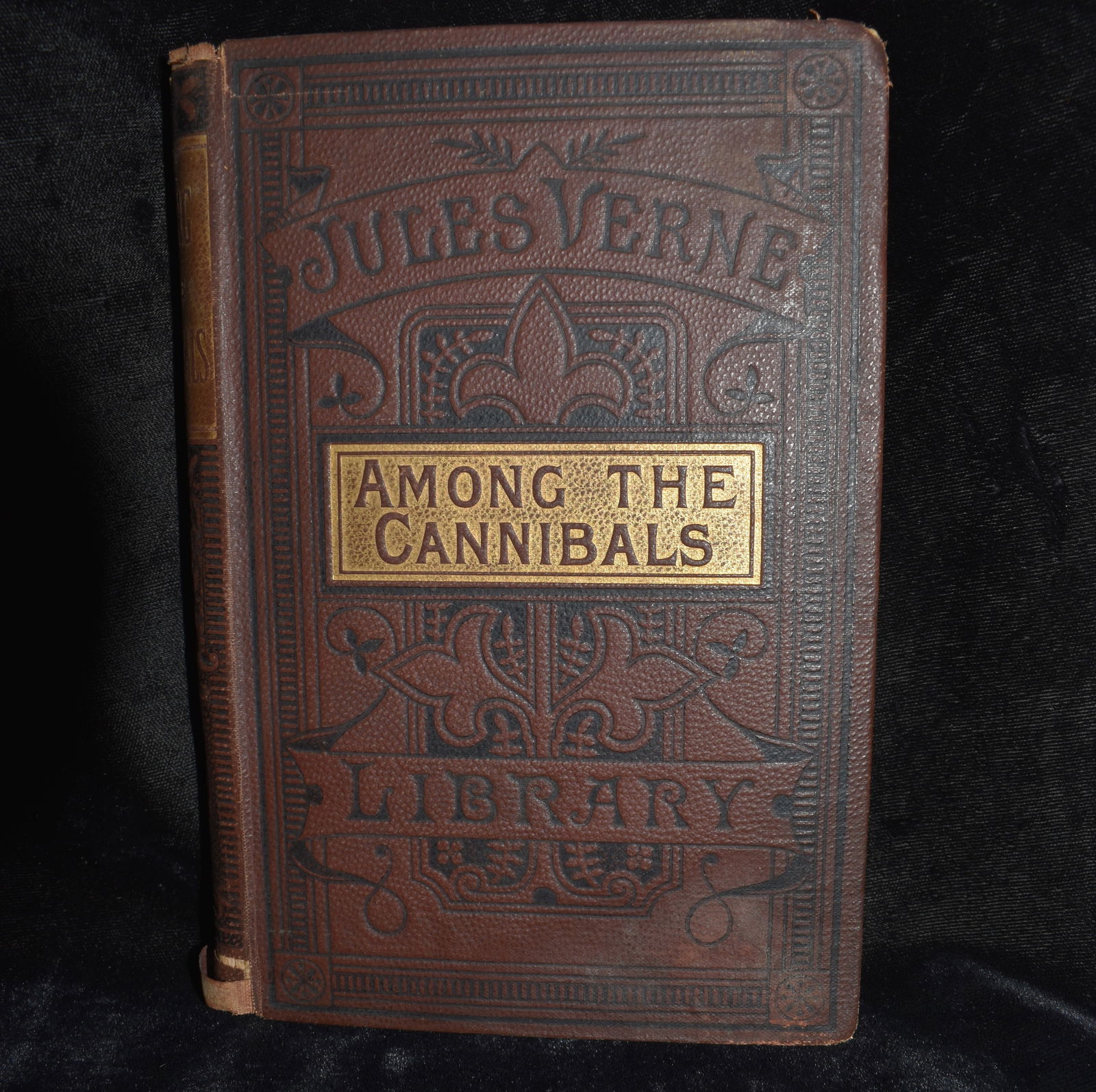 1899 Among The Cannibals by Jules Verne: Among The Cannibals by Verne, Jules. Published by WARD LOCK AND CO circa 1899. Original cloth hardback with gold gilt. Spine has some wear, inpage to title plate are seperated as shown in photos. Age