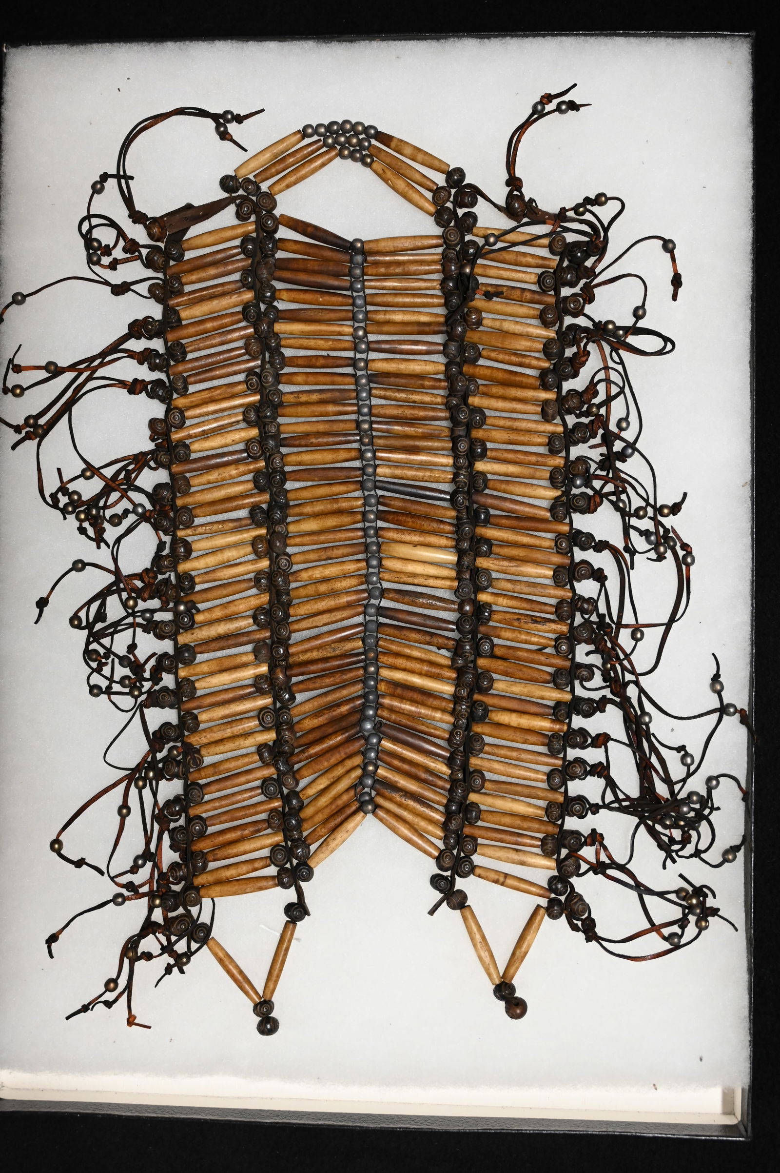 Old Bone Breast Plate w/metal beads displayed in a 14" x 20" case.: Old Bone Breast Plate w/metal beads displayed in a 14" x 20" case.