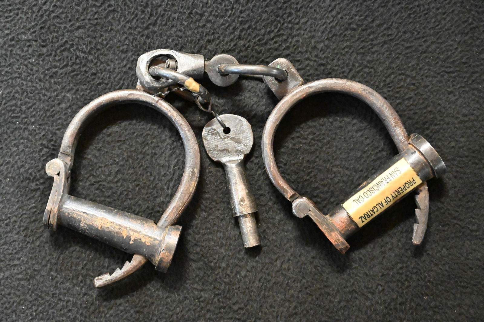 Hinged Handcuffs with key. Has Property of Alcatraz plaque on them. Possibly modern reproductions: Hinged Handcuffs with key. Has Property of Alcatraz plaque on them. Possibly modern reproductions or embellished with the plaque.