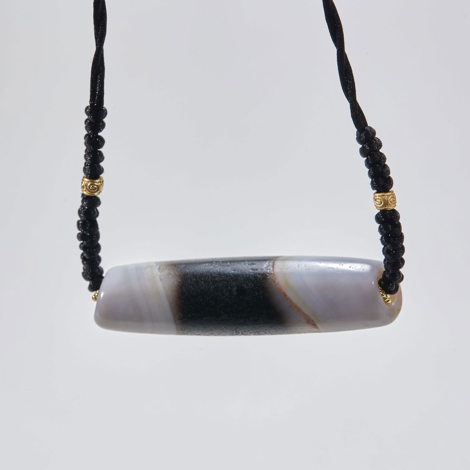 Pendant with black and white agate beads: Agate Black and White Bead Pendant, L: 5.7cm, D: 1.5cm, 23g. Passed down or unearthed in the Xizang area, it is a Tibetan Buddhism accessory made of natural banded agate with distinct black and white