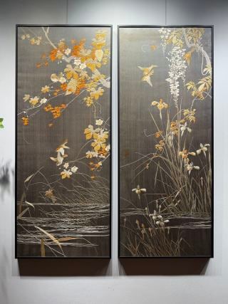 A pair of fine flower and bird embroidery in the Republic of China: It is a set of two vertical sets of hanging screens with a dark gray background, with gold, white and orange as the main colors. The picture depicts the waterside scenery, the branches are full of