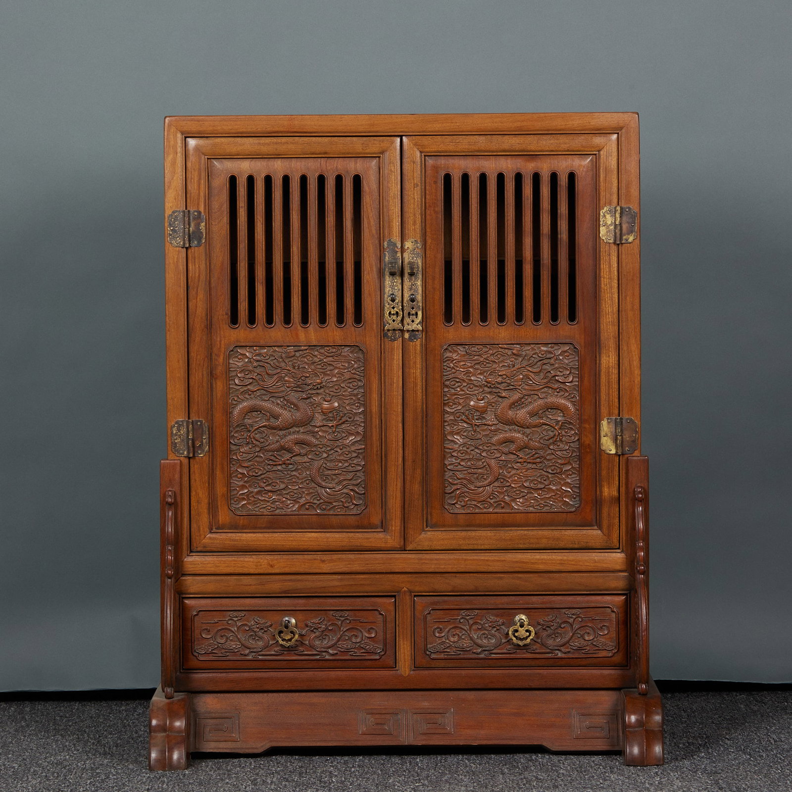 Huanghuali engraving dragon pattern multi-treasure cabinet: Wooden vertical cabinet, with warm wood color. For the cabinet door, the upper part is vertically hollowed out, and the lower part of the cabinet door is embossed with Yunlong pattern, Xiangyun