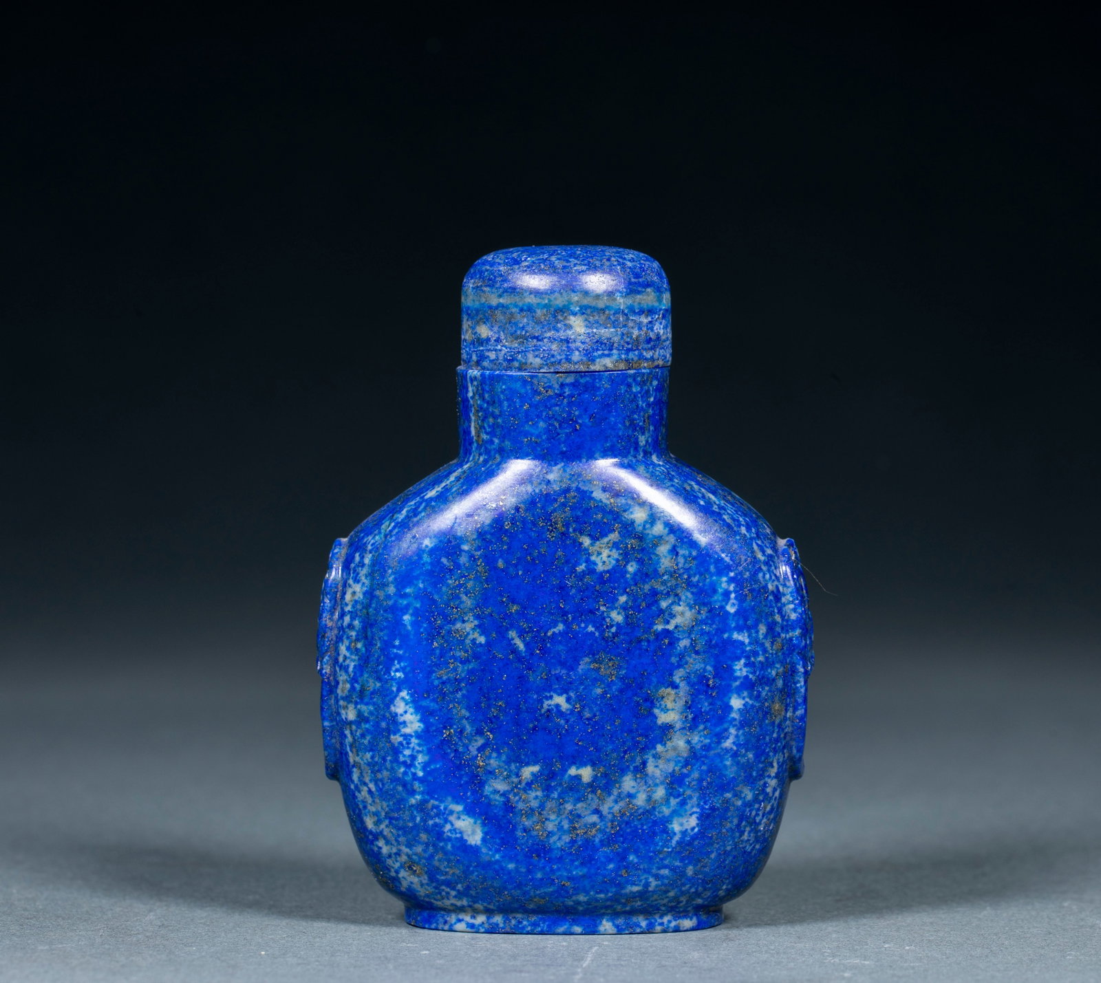 Lapis lazuli snuff bottle: The whole lapis lazuli is carved, and the pot body is covered with lapis lazuli's iconic blue land, Venus and white spots. The animal heads are carved on both sides, and the original pot cover is