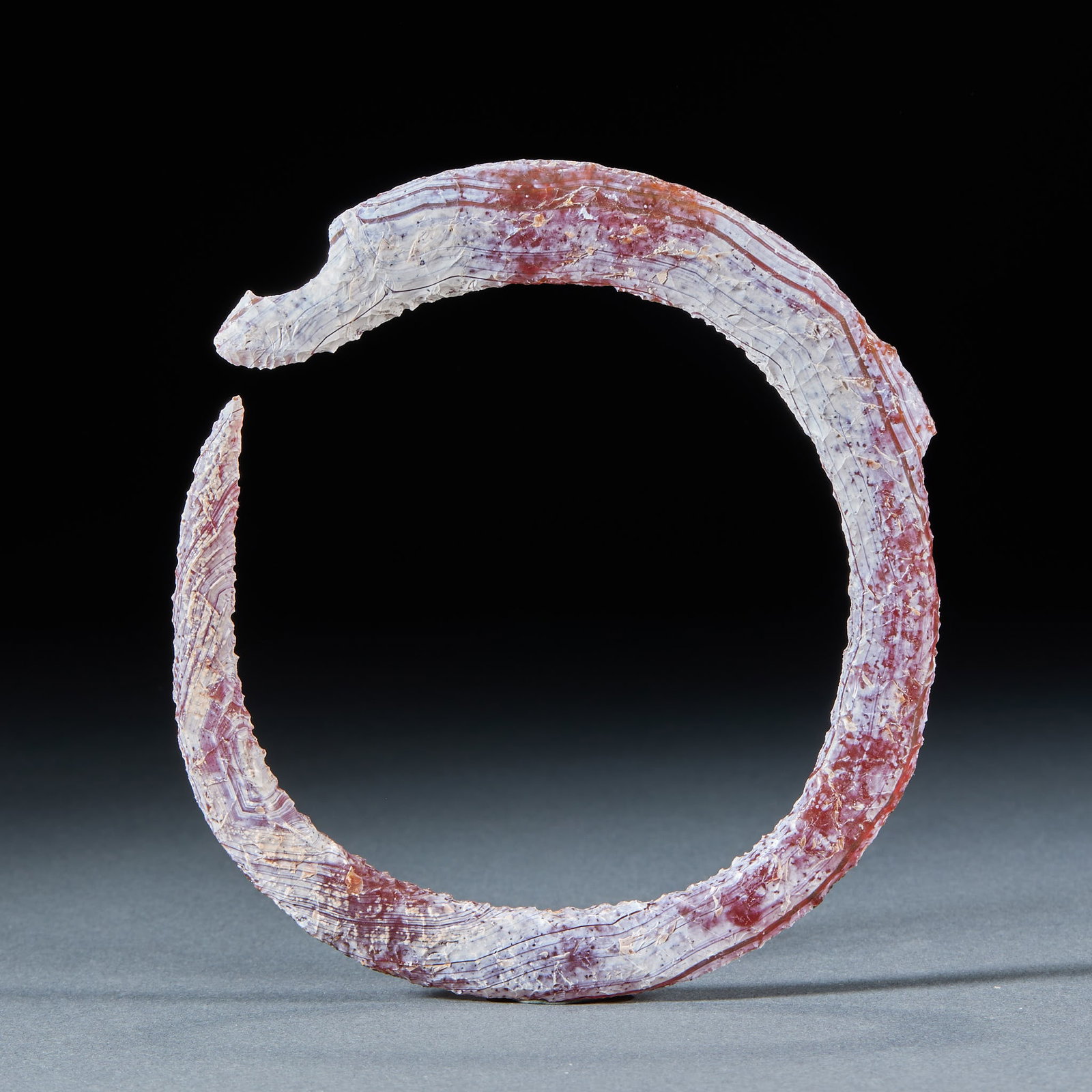 Agate c-shaped dragon: Agate texture, the whole is a C-shaped open dragon, and one end is carved with a dragon head. The body is covered with silk-winding texture, with dense surface weathering traces, alternating red and