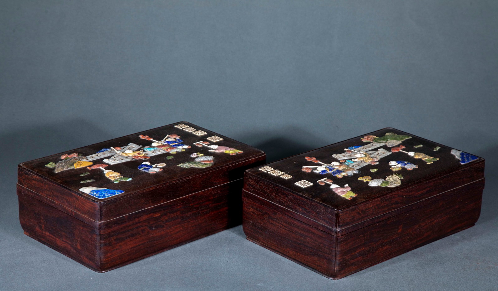 A pair of rosewood cover boxes inlaid with baby play pictures in Qingganlong: In pairs, rosewood is the fetus. The box body is square, and the surface of the box cover is inlaid with various kinds of jade, mother-of-pearl and precious stones. The children have different