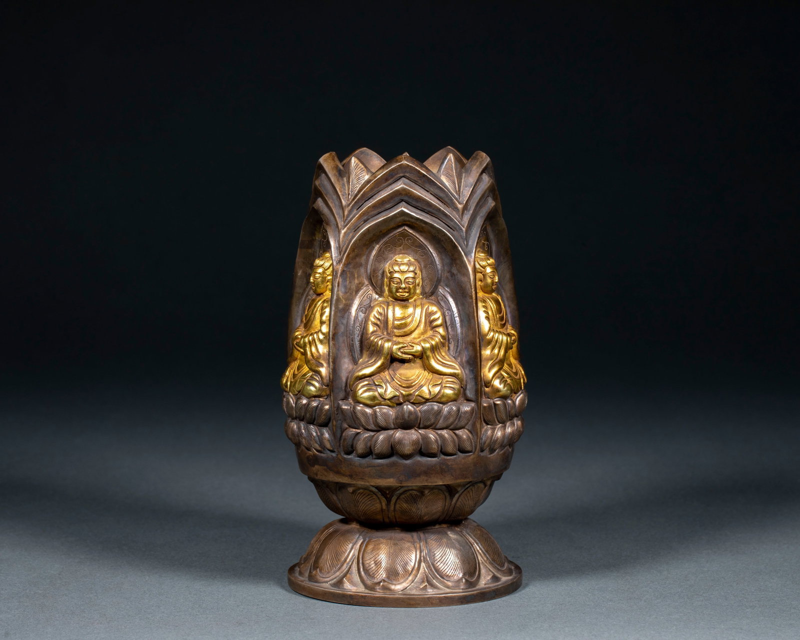 Silver-gilded Buddha statue donor: Silver lotus bud container, the body of which is shaped like a lotus bud, and the wall of the container is provided with three niches for opening windows, in which the Buddha is seated with gold, and