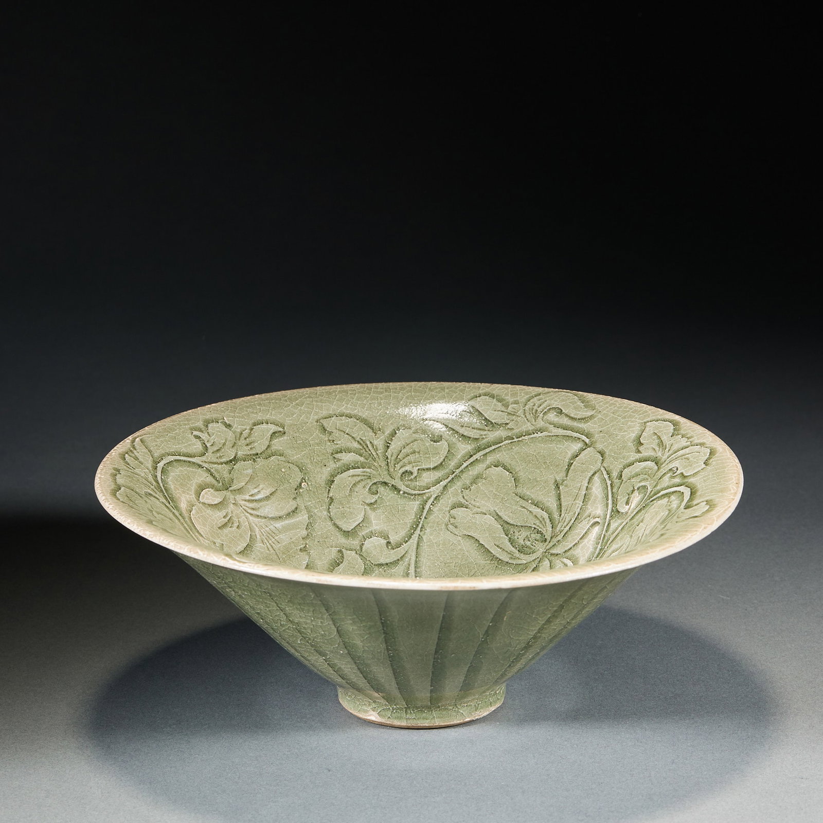 Yaozhou kiln flower pattern hat bowl: The bowl is hat-shaped, open, inclined and straight, with a small circle. Apply green glaze all over the body, and the glaze is covered with pieces. The bowl is carved with flowers wrapped in
