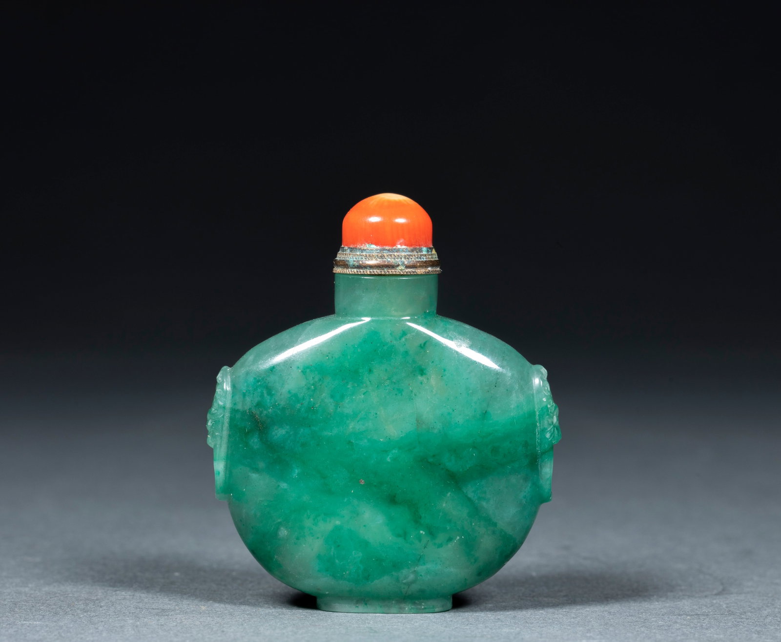 Emerald snuff bottle: Jade texture, flat belly, carved animal heads on both sides to spread the first ears. The pot body has a plain surface, and natural emerald green floating flowers and stone patterns can be seen