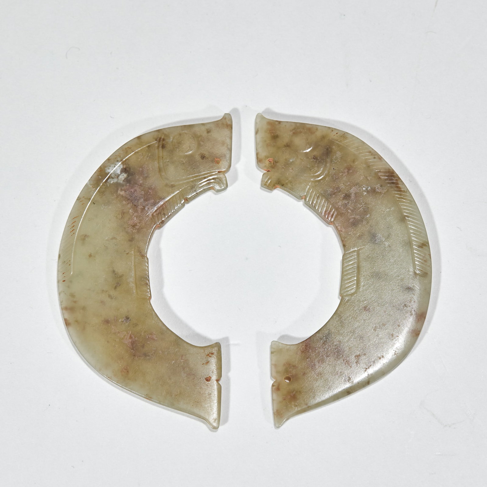 Jade fish couple.: The two pieces are paired in a semi-circular arc shape, and the fish heads are carved at both ends. The negative line of the vessel body is engraved with fish's eyes, gills and fins, and brown spots