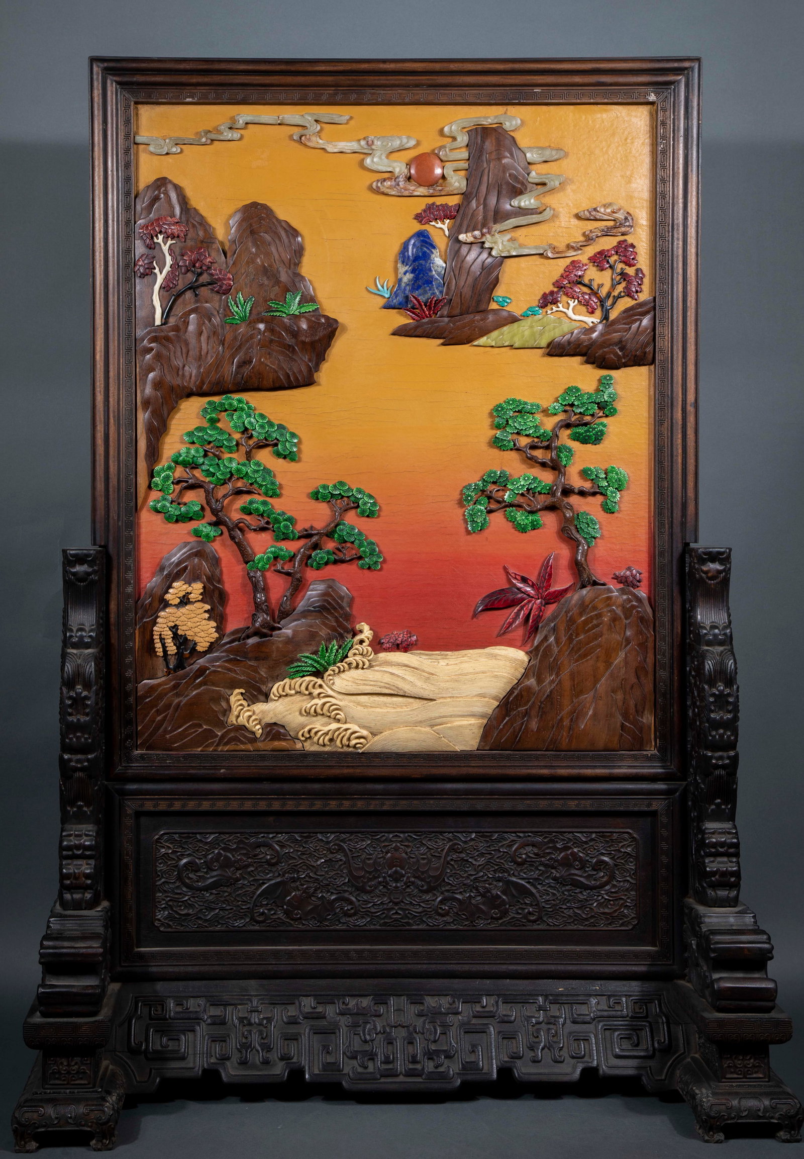 Green rosewood inlaid with treasure, rising sun and rising sun inserted into the screen: The outer frame and base are made of rosewood, and the base is carved with bats and grass-rolling palindromes. The screen is painted yellow and red gradually, and many materials such as wood, jade,