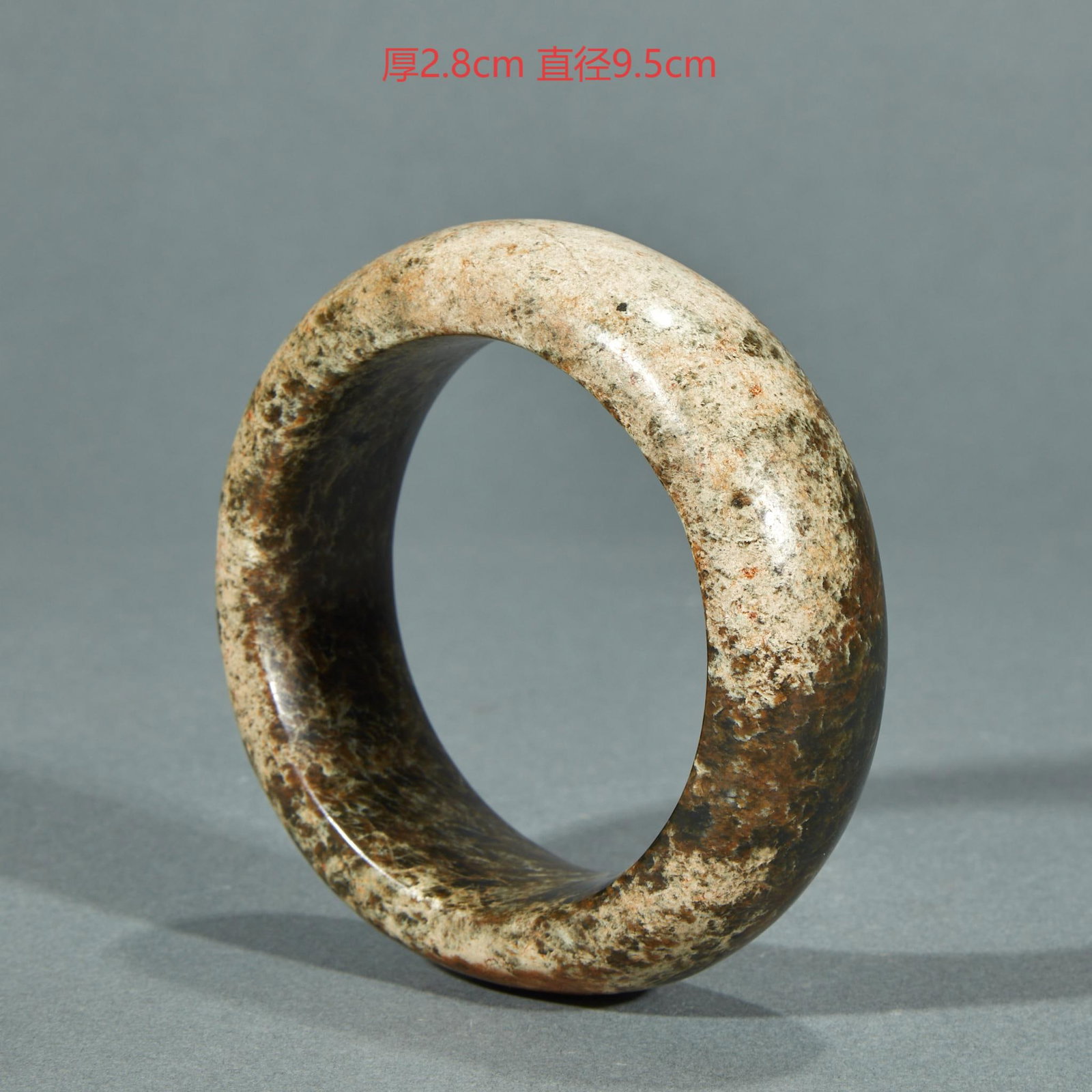 Jade arm ring before Ming dynasty: Wide thick-walled jade bracelet, whose surface is covered with gray and dark brown spots, thick patina, stocky shape, and rounded inner and outer walls.2.8cm thick and 9.5cm in diameter.