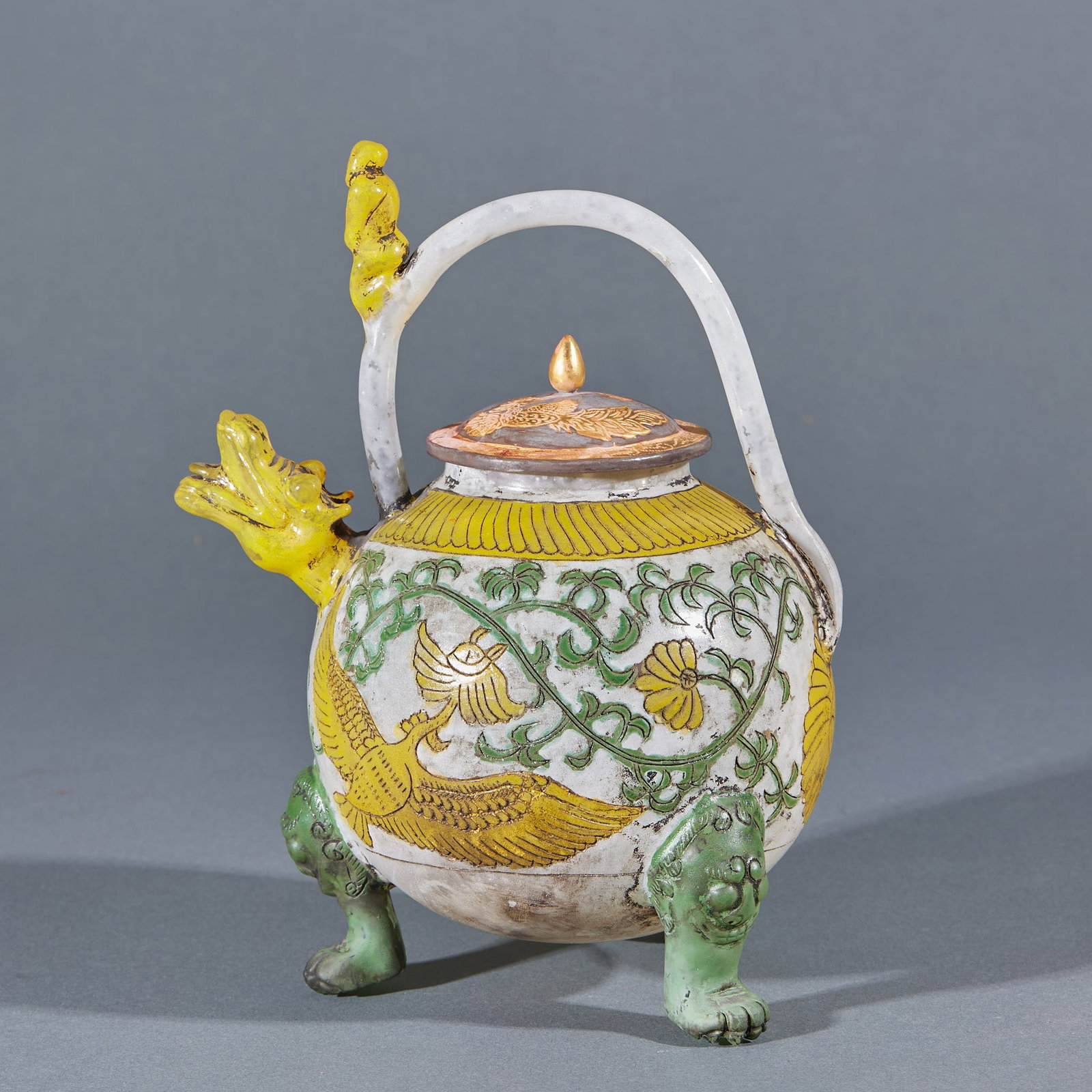 Glass ladle girder pot: The spherical pot body is decorated with white glaze and yellow and green colors. The pot body is carved with phoenix and tangled flowers. The spout is shaped like a dragon head, the lifting beam is