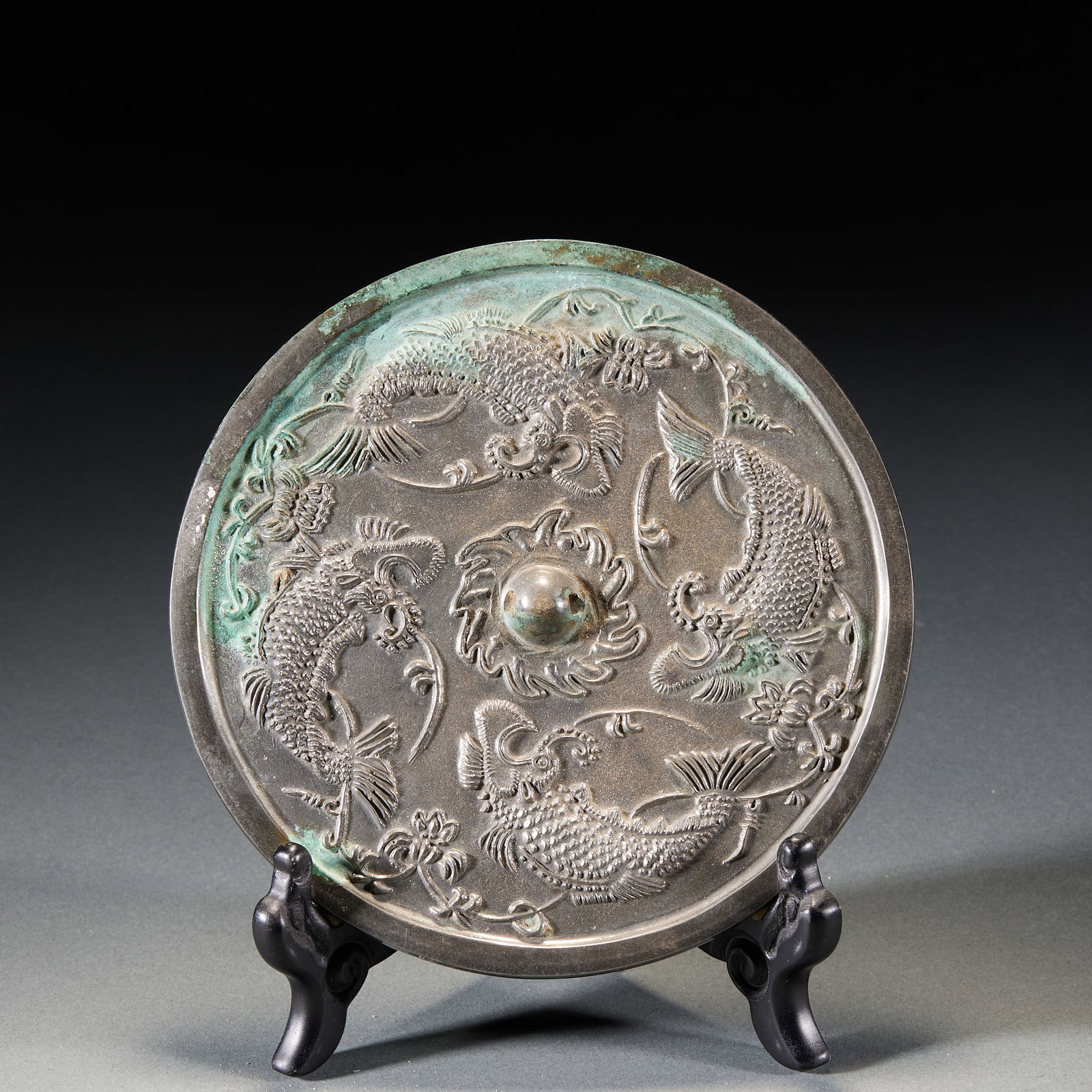 Four fish bronze mirrors before Ming dynasty: Round bronze mirror, the mirror button is spherical, and the mirror center button seat is carved with lotus patterns. On the back of the mirror, the main body is embossed with four-tailed fish