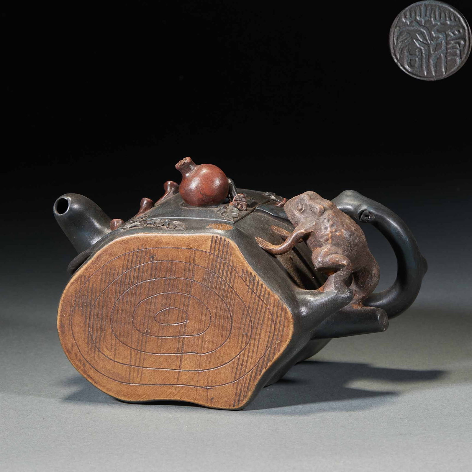 Jiang Rong pomegranate golden toad teapot: The teapot imitates the shape of the stump, and the bottom imitates the tree ring texture. A toad is molded at the handle, pomegranate fruit is decorated at the lid, and the body is decorated with bra