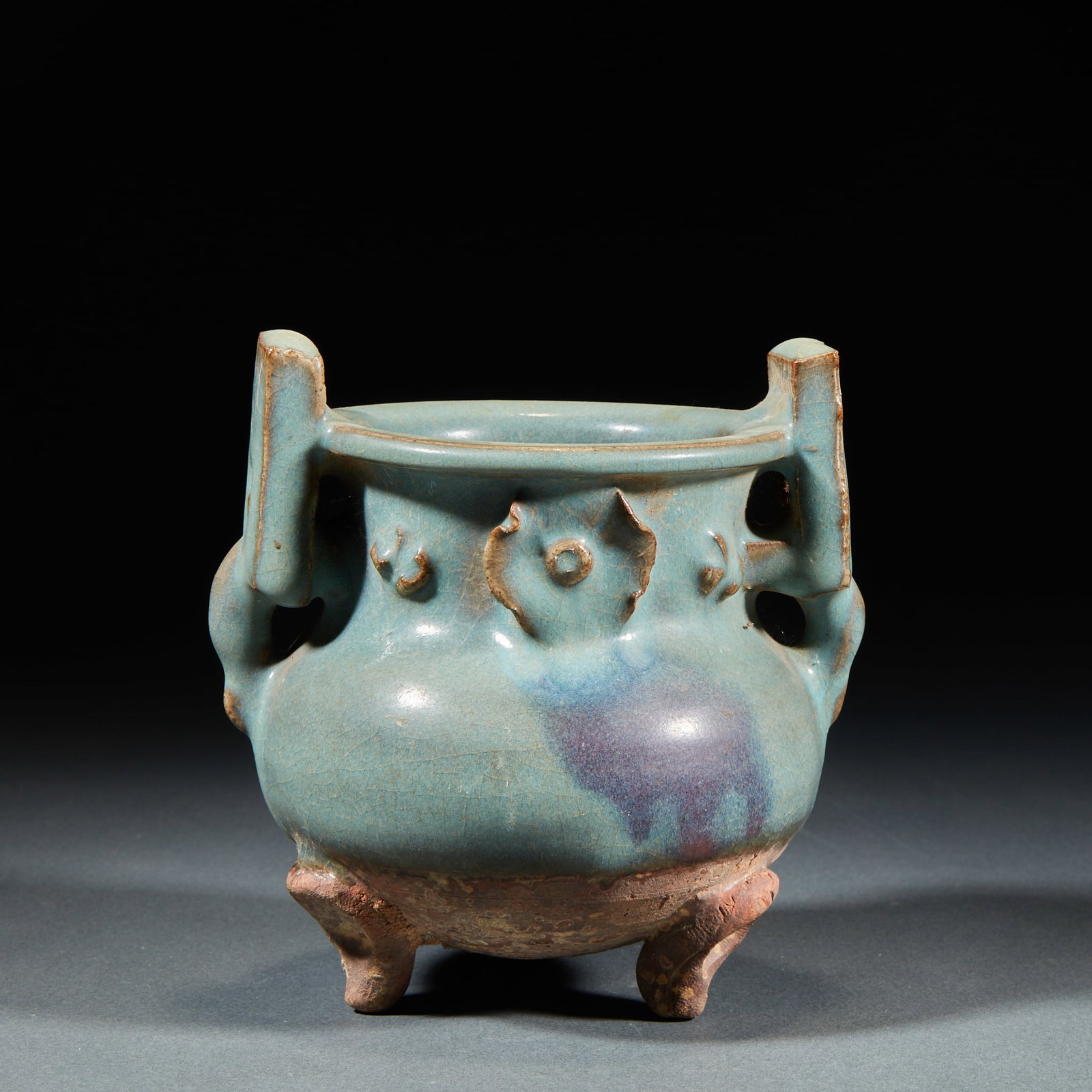 Ruyao three-legged furnace: Azure glaze is applied to the furnace body, and purple-red kiln patches are distributed locally, and the glaze is covered with pieces. The mouth is curled outward, and the neck is decorated with